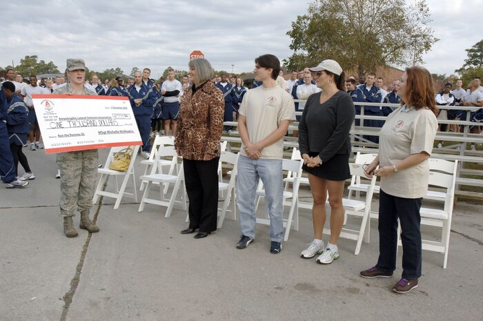 Master Sgt. Michelle McMeekin presents a $1,000 check from the Charleston Top 3 organization to the Amyotrophic Lateral Sclerosis Association prior to the start of the Run the Runway 5K event honoring retired Brig. Gen. Thomas Mikolajcik here on Wingman Day Nov. 17. The money donated to the ALS Association was raised through the sale of custom designed t-shirts worn on the day of the event. Sergeant McMeekin is assigned to the 437th Force Support Squadron and represented the Charleston Top 3. (U.S. Air Force photo/Staff Sgt. Marie Brown)