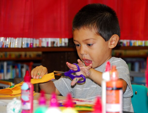 Gregory Calas concentrates on cutting his craft paper during Family Craft Night at the Base Library here Nov. 12. Gregory worked with his grandmother Nitsa Calas during the two-hour craft night to build a Thanksgiving turkey made of paper. Mrs. Calas is the wife of Army Ch. Capt. Lyde Calas who is deployed to the Middle East. (U.S. Air Force photo/Staff Sgt. Daniel Bowles)