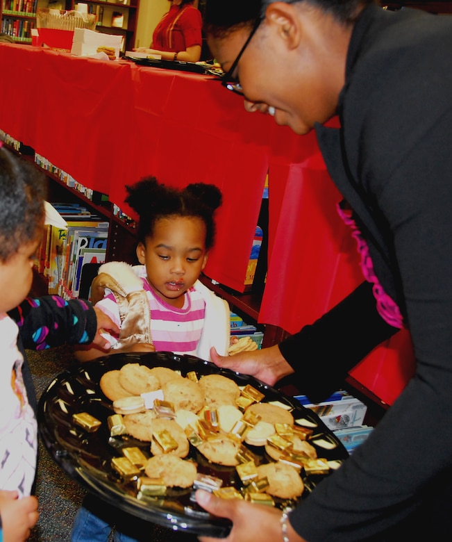 Senior Airman Jasmine Rhodes offers her daughter Maliyah a cookie during Family Craft Night at the Base Library here Nov. 12. The Base Library holds craft nights throughout the holiday season for Halloween, Thanksgiving and Christmas to bring parents and children together in a fun-filled atmosphere. Airman Rhodes is a help desk technician with the 437th Communications Squadron. (U.S. Air Force photo/Staff Sgt. Daniel Bowles)