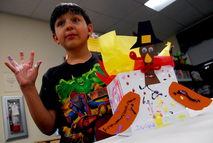 Jeffery Scott raises a sticky hand full of paint and glue during the Family Craft Night held at the Base Library here Nov. 12. Jeffery was joined by his sister Ashley in constructing a Thanksgiving turkey covered with messages and the names each member of their family. Jeffery is the son of Master Sgt. Donald Scott who is with the 437th Maintenance Operations Squadron. (U.S. Air Force photo/Staff Sgt. Daniel Bowles)