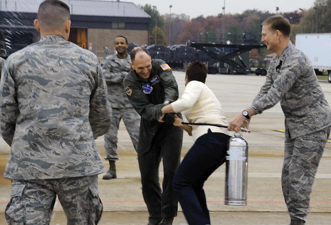 Major Gen. Ralph Jodice, Air Force District of Washington commander, wrestles with his wife Judy over a fire extinguisher she and Col. Phillip Gibbons, AFDW vice commander, were using to try to douse him with after his final flight Tuesday at Joint Base Andrews Naval Air Facility Washington. General Jodice was welcomed back to Andrews by base leaders, after flying over the Pentagon and Capitol, with a tradition that dates back to the Vietnam War era, when pilots who completed 100 safe combat missions were doused down with fire hoses upon landing. On Wednesday, General Jodice is slated to pass the AFDW guidon to Maj. Gen. Darrell Jones during a change of command ceremony in Hangar 3 at Andrews. (U.S. Air Force photo/ Ben Newell)