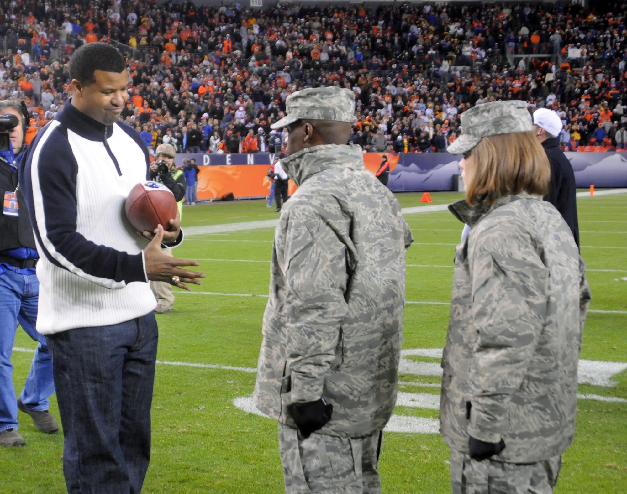 DENVER -- Former Denver Broncos safety Steve Atwater presents a souvenir game ball to the Peterson Air Force Base contingent during the Denver Bronco’s Military Appreciation Monday, a salute to the United States military, Nov. 2 at Mile High stadium. Accepting the game ball is Master Sgt. Brandon English, 21st Operations Group first sergeant, followed by Airman 1st Class Kimberly Atwood, 21st Medical Group. The Broncos and their fans gave the attending Airmen, Soldiers, Marines and Sailors a rousing ovation during the halftime festivities. (Air Force photo by Walt Johnson)