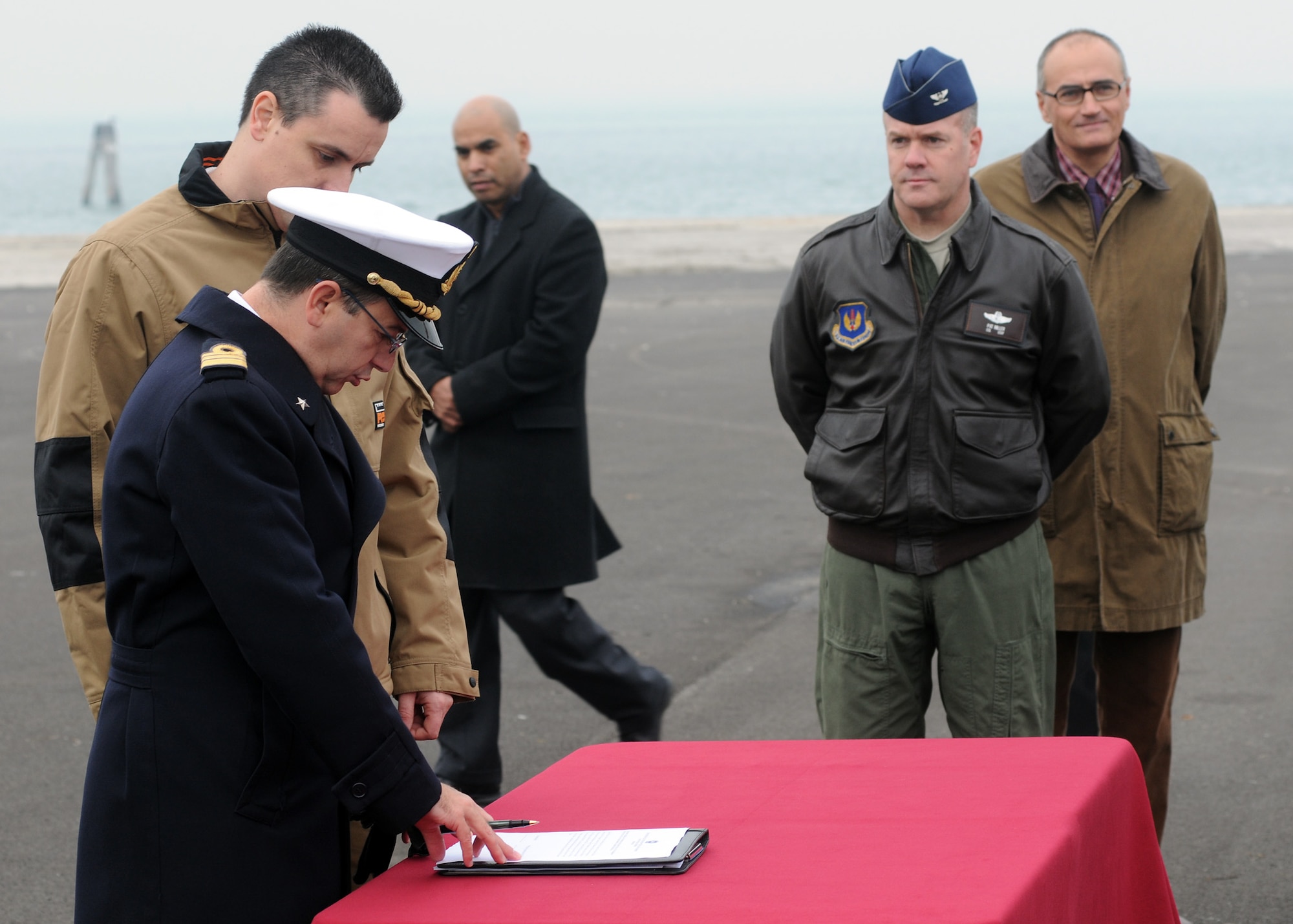Col. Patrick Miller, 31st Operations Group commander from Aviano Air Base, Italy, looks on as Italian Navy Commander Franco Maltese signs a document transferring control of an aircraft wreckage to an Italian aero club during a ceremony at the Chioggia Lagoon Nov. 14, 2009.  Aeroclub “Ferrarin” in Thiene will try to restore the wreckage, believed to be a World War II Army Air Force P-47 Thunderbolt fighter, recovered from the Adriatic Sea during a fishing expedition in May 2009.  (U.S. Air Force photo/Airman LaVel D. Sterling)