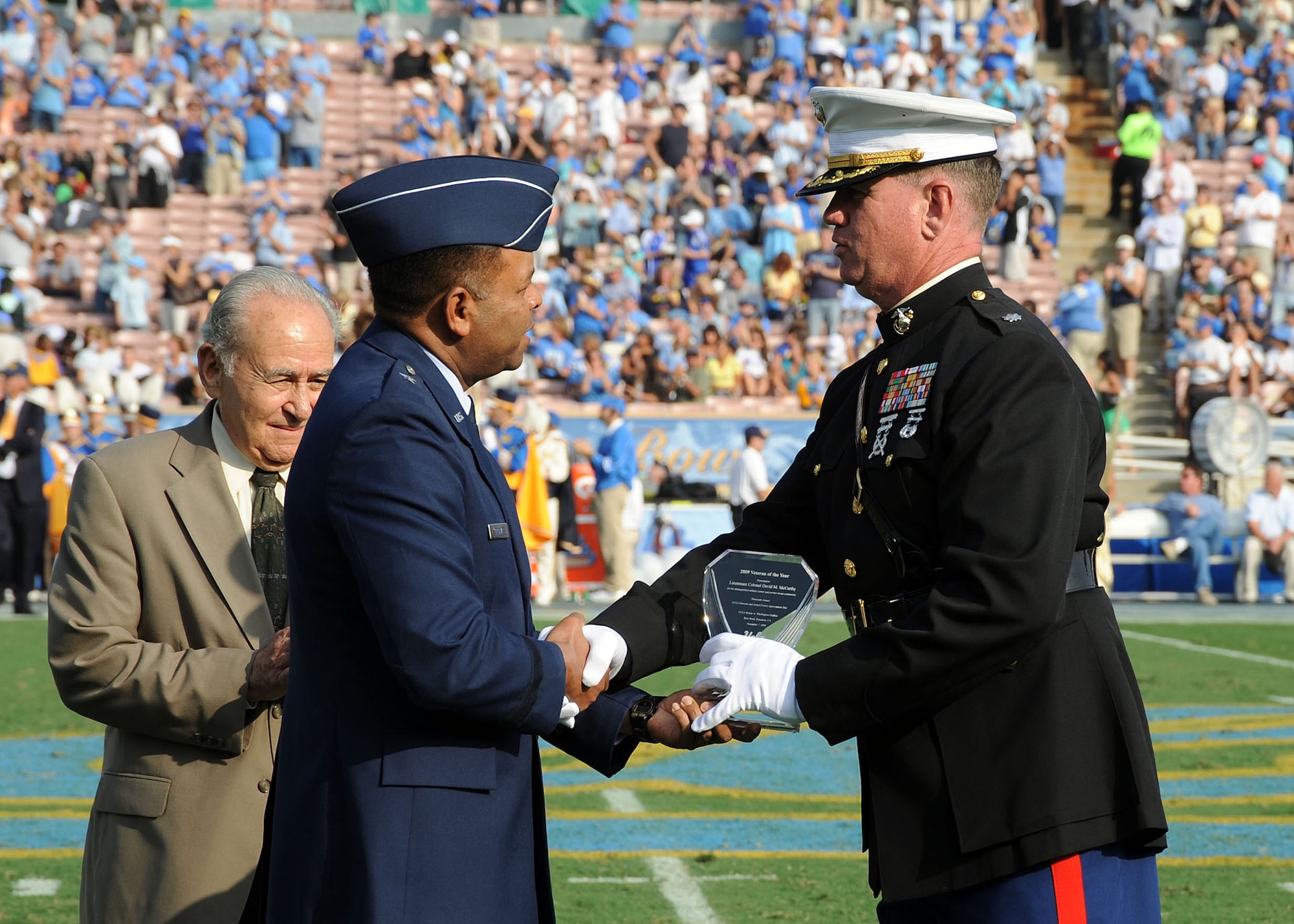 Brig. Gen.  Samuel Greaves (center), Space and Missile Systems Center vice commander, presents the “2009 Veteran of the Year” award to Marine Corp Lt. Col. David McCarthy (right) during the halftime ceremony at the UCLA Veterans and Military Appreciation football game held at the Rose Bowl Stadium, Pasadena, Nov.  7.  Army Reserve Ambassador Emeritus Ronald Markarian (left), California State Director of the U.S. Selective Service System, also participated in the ceremony. The UCLA Bruins won the game played against the Washington Huskies.  (Photo by Lou Hernandez)