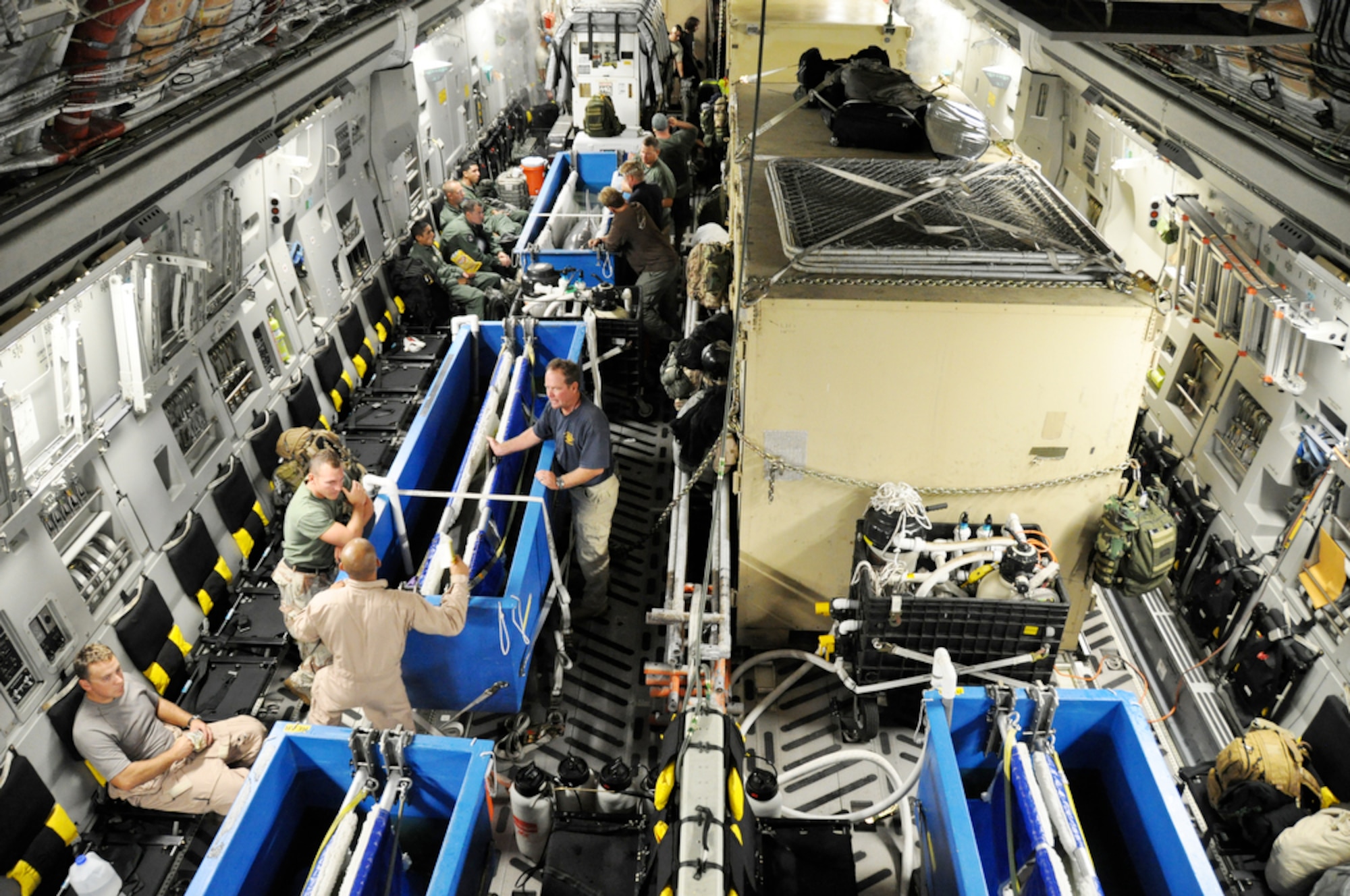 Airmen, Sailors and contractors talk and manage dolphins while aboard a C-17 Globemaster III Nov. 8, 2009, en route to New Caledonia. The crew is taking the Sailors and dolphins to Noumea, New Caledonia, where they will participate in Lagoon Minex 2009, which is a humanitarian project where U. S. Navy, French, Australian and New Zealand demolition crews will remove mines left over from World War II from the surrounding water of the area. The Airmen are from Hickam Air Force Base, Hawaii, the Sailors are from Navy Mobile Unit 1 from San Diego, and contractors are from the Navy Marine Mammals Program. (Defense Department photo/Tech. Sgt. Cohen A. Young)