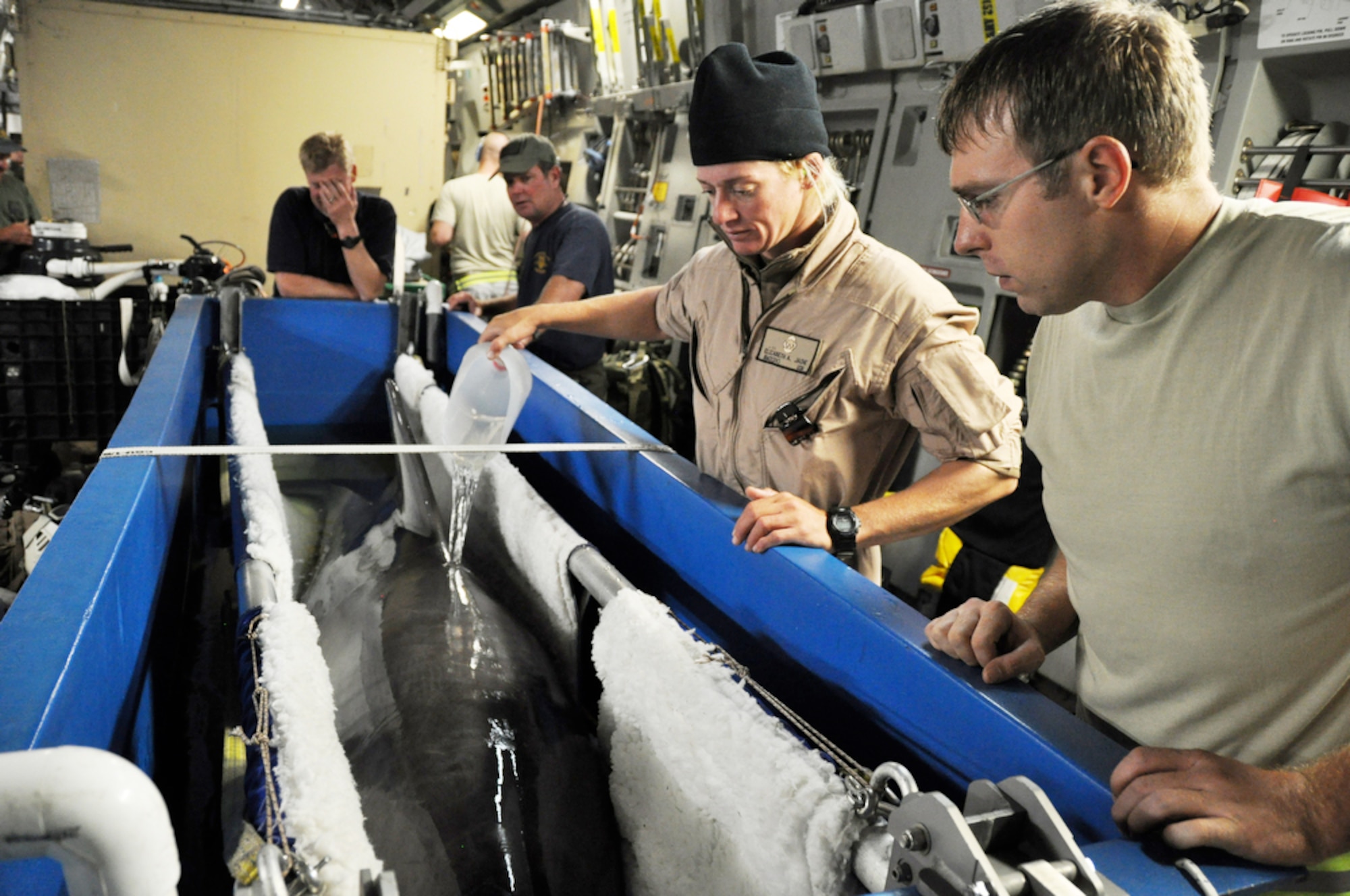 Staff Sgt. Ray Nealon watches as Navy Petty Officer 2nd Class Elizabeth Jache pours water on her dolphin to keep him cool prior to transporting him from a C-17 Globemaster from March Air Reserve Base, Calif., to a C-17 from Hickam AFB, Hawaii, Nov. 8, 2009. Petty Officer Jache is one of the primary dolphin handlers in the Navy Marine Mammal Program based in San Diego. The Air Force active duty and Reserve C-17 aircrews transported four dolphins from the mammal program to Noumea, New Caledonia, where they will participate in Lagoon Minex 2009, which is a humanitarian project where U.S. Navy, French, Australian and New Zealand demolition crews will remove mines left over from World War II from the surrounding water of the area. Sergeant Nealon is assigned to the 735th Air Mobility Squadron at Hickam AFB. He is a native of Wilkes-Barre, Pa. (Defense Department photo/Tech. Sgt. Cohen A. Young)