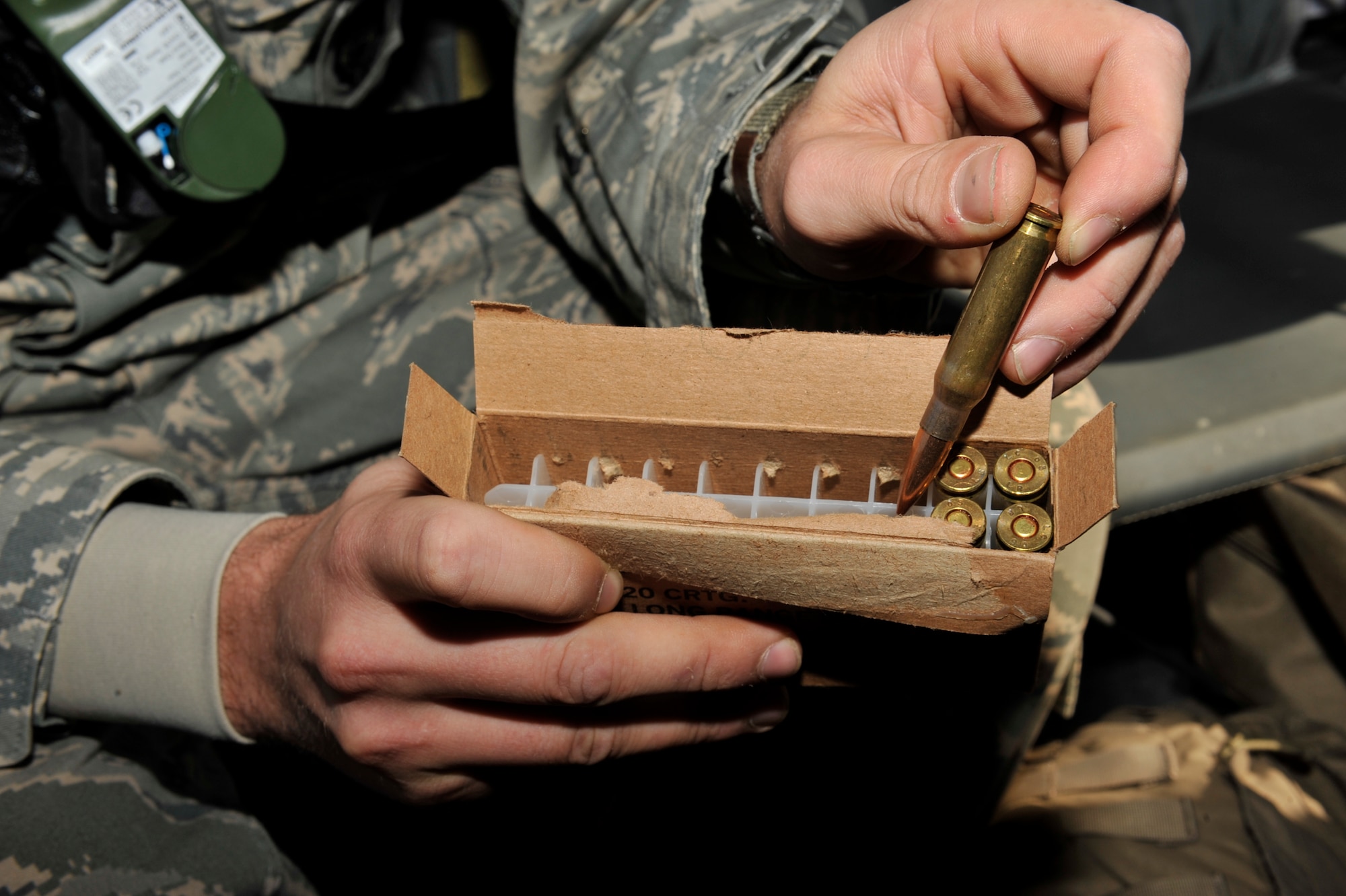 Staff Sgt. Joshua Beach, 19th Security Forces Squadron resource protection manager, extracts a 7.2 mm long-range bullet for Sergeant Hook, while engaging targets for training at Fort Chaffee, Ark., Nov. 2. Sergeant Beach handled the cartridge of bullets for Sergeant Hook during sniper training in a helicopter. (U.S. Air Force photo by Airman 1st Class Lausanne Pacheco)