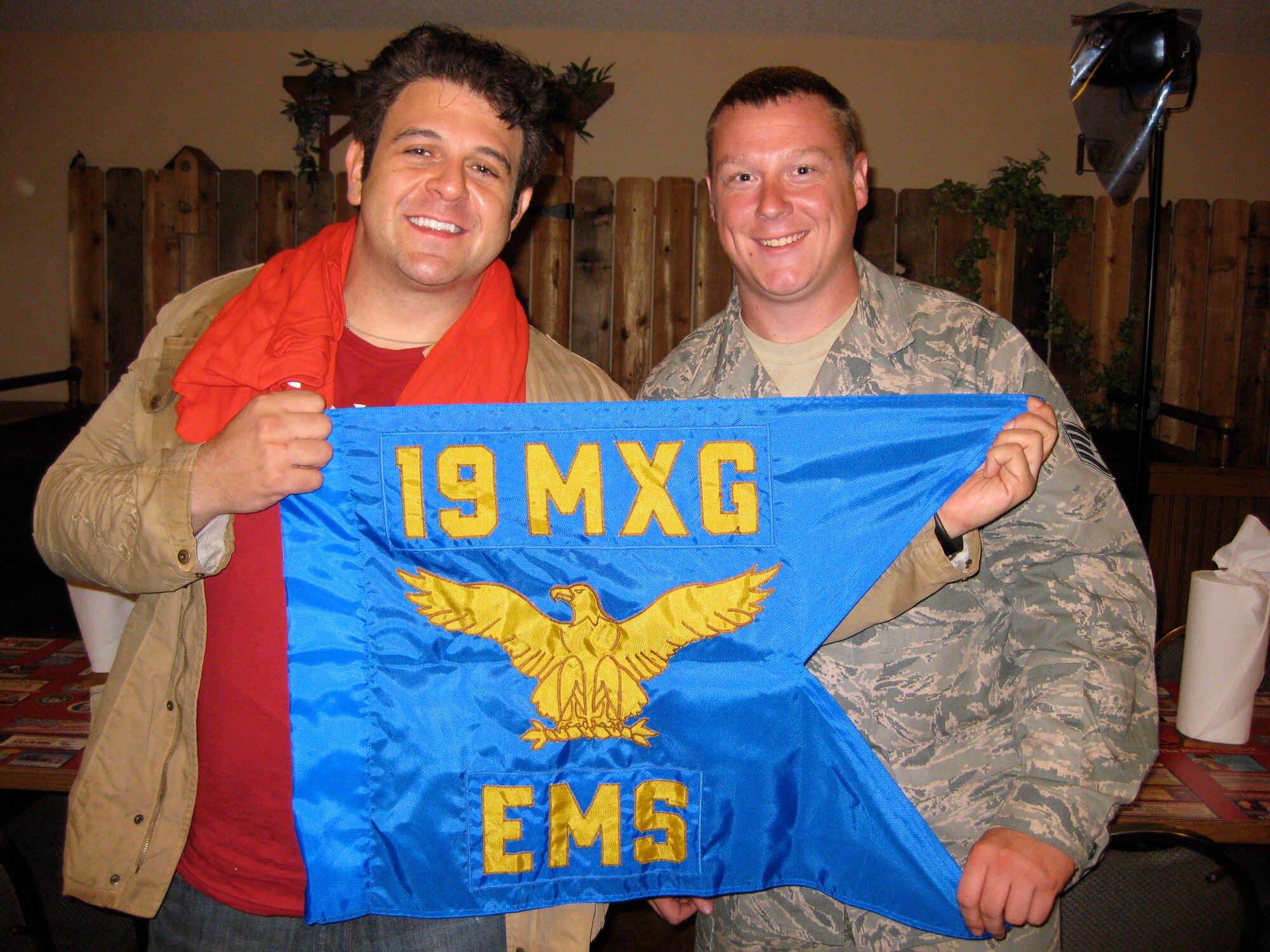 Man vs. Food Host Adam Richman displays the 19th Equipment Maintenance Squadron guidon with Staff Sgt. Sean Tutrow, 19 EMS aerospace ground equipment journeyman. The show taped segments in central Arkansas earlier this year and will air Nov. 25 on the Travel Channel. (Courtesy photo)