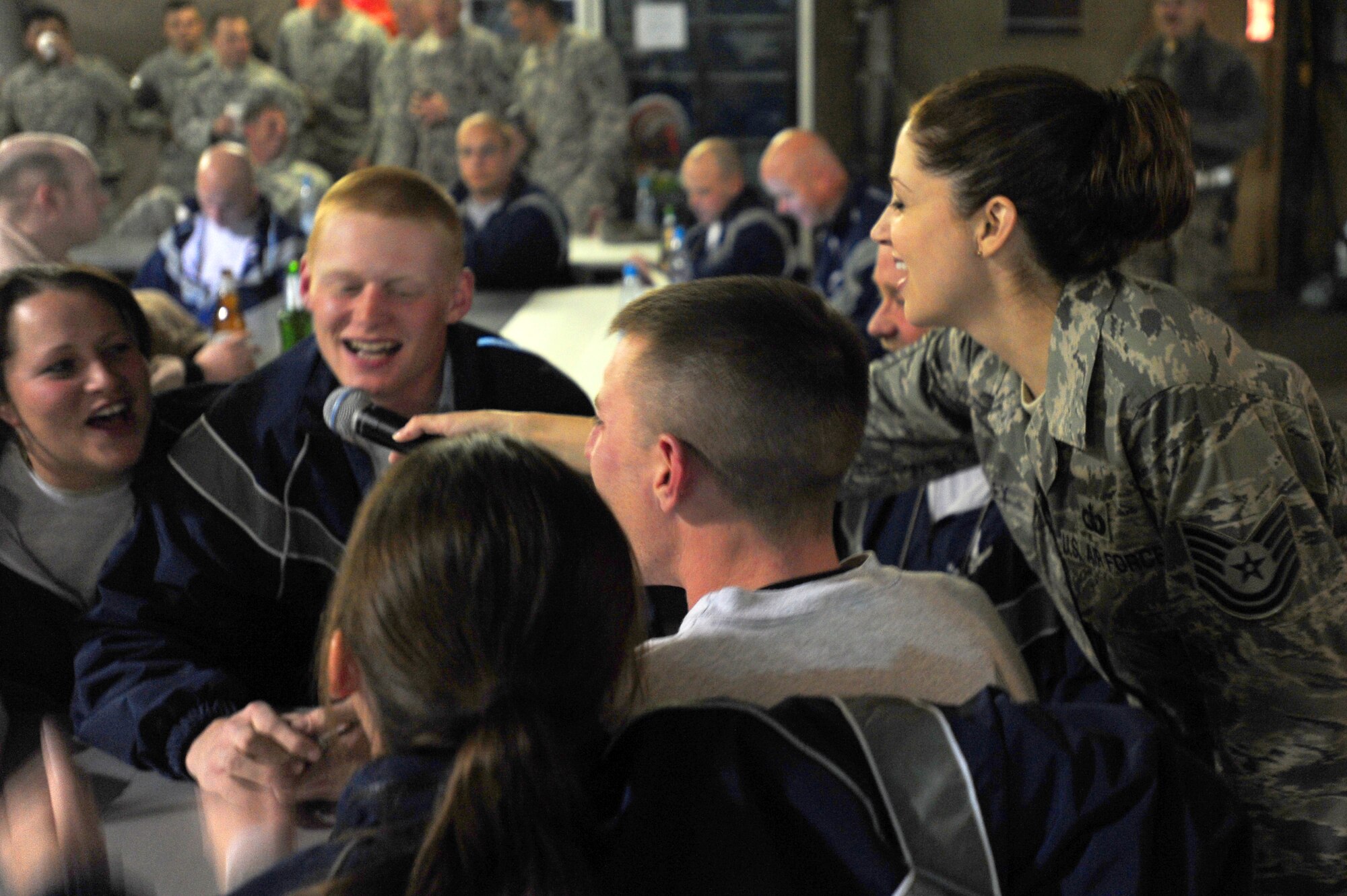 TRANSIT CENTER AT MANAS, Kyrgyzstan -- Tech. Sgt. Christin Foley, U.S. Air Forces Central Sirocco Band vocalist, shares the microphone with Airmen during a performance at Pete's Place, Nov. 15, 2009. The Sirocco Band is stationed at a base in Southwest Asia and is deployed from Lackland Air Force Base, Texas. (U.S. Air Force photo/Senior Airman Steele C. G. Britton)