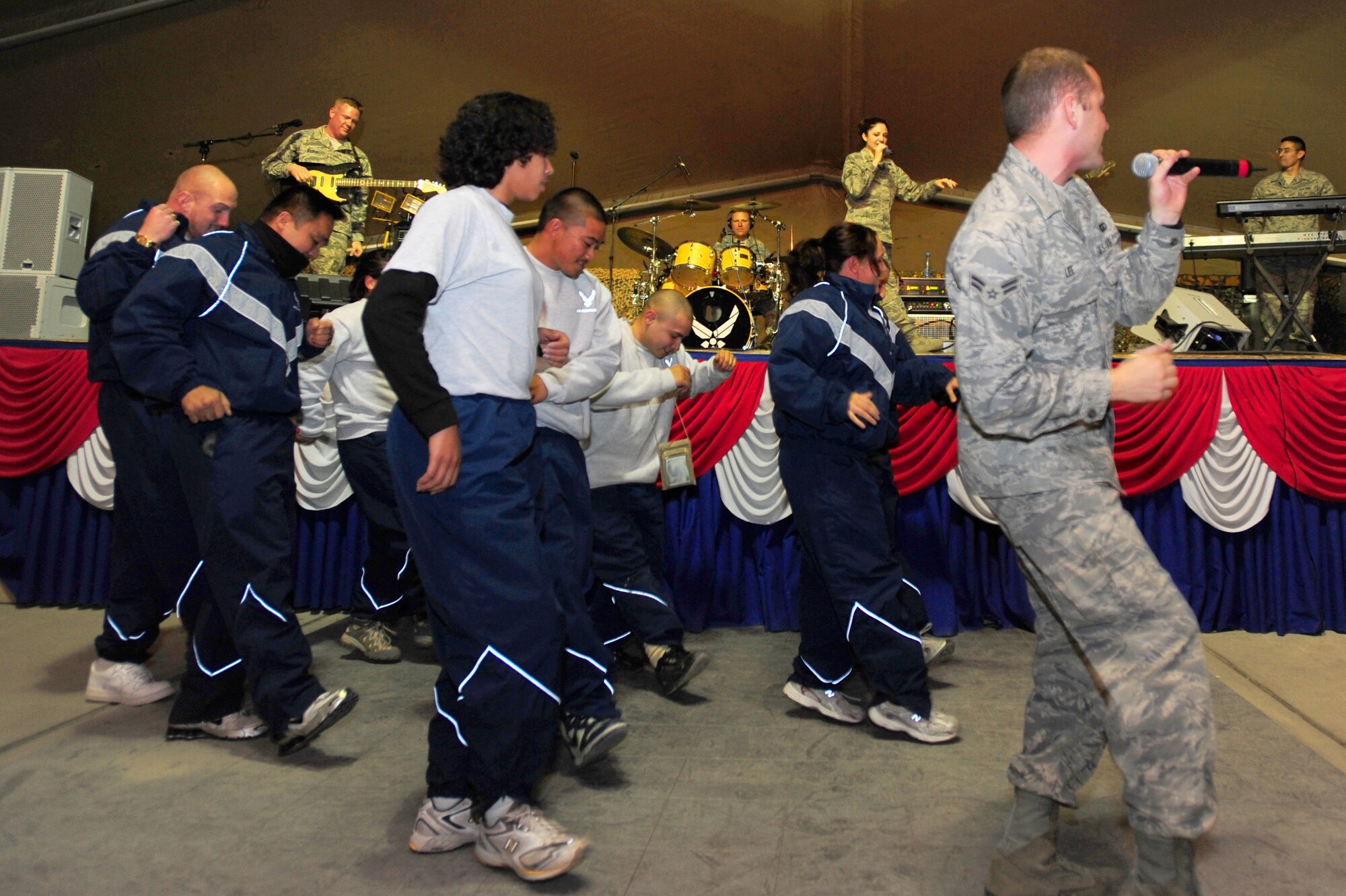 TRANSIT CENTER AT MANAS, Kyrgyzstan -- Airman 1st Class Clayton Lee, U.S. Air Forces Central Sirocco Band vocalist, leads Airmen in the popular "Cupid Shuffle" during a show at Pete's Place, Nov. 15, 2009. The Sirocco Band is stationed at a base in Southwest Asia and is deployed from Lackland Air Force Base, Texas. (U.S. Air Force photo/Senior Airman Steele C. G. Britton)