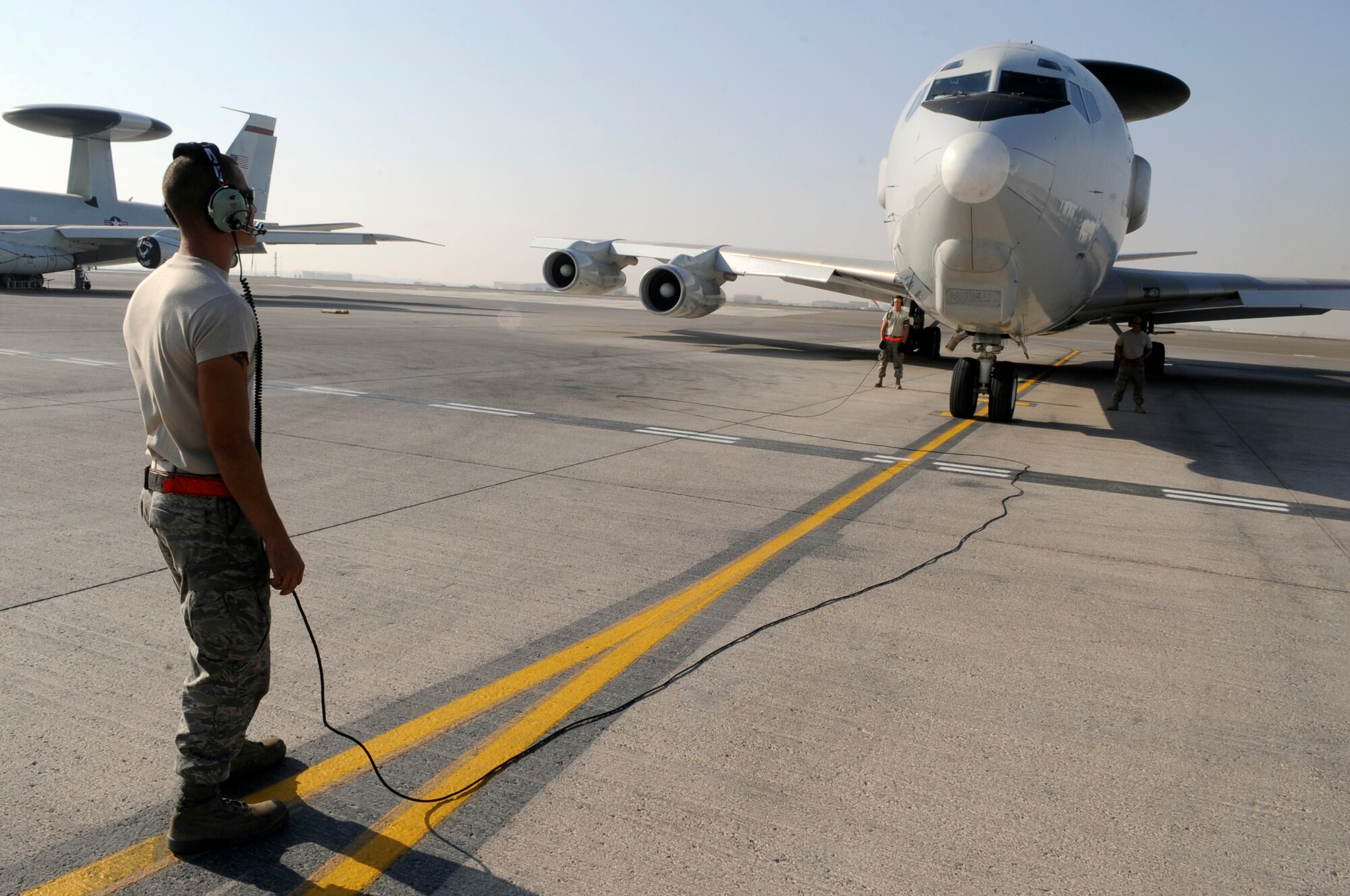 SOUTHWEST ASIA – Airman 1st Class Brandon Posey, 380th Expeditionary Aircraft Maintenance Squadron, communicates with crew members as Senior Airman Brandon Camber and Staff Sgt. Thomas Wilson, 380th EAMXS, standby to clear the chocks, before an E-3 Sentry taxis to take-off in support of Operation Enduring Freedom Nov. 16, 2009. They are deployed from Tinker Air Force Base, Okla. Airman Posey calls Destin, Fla., home. Airman Camber grew up in Georgetown, Calif., and Sergeant Wilson hails from Dallas, Texas. (U.S. Air Force photo/Senior Airman Stephen Linch)