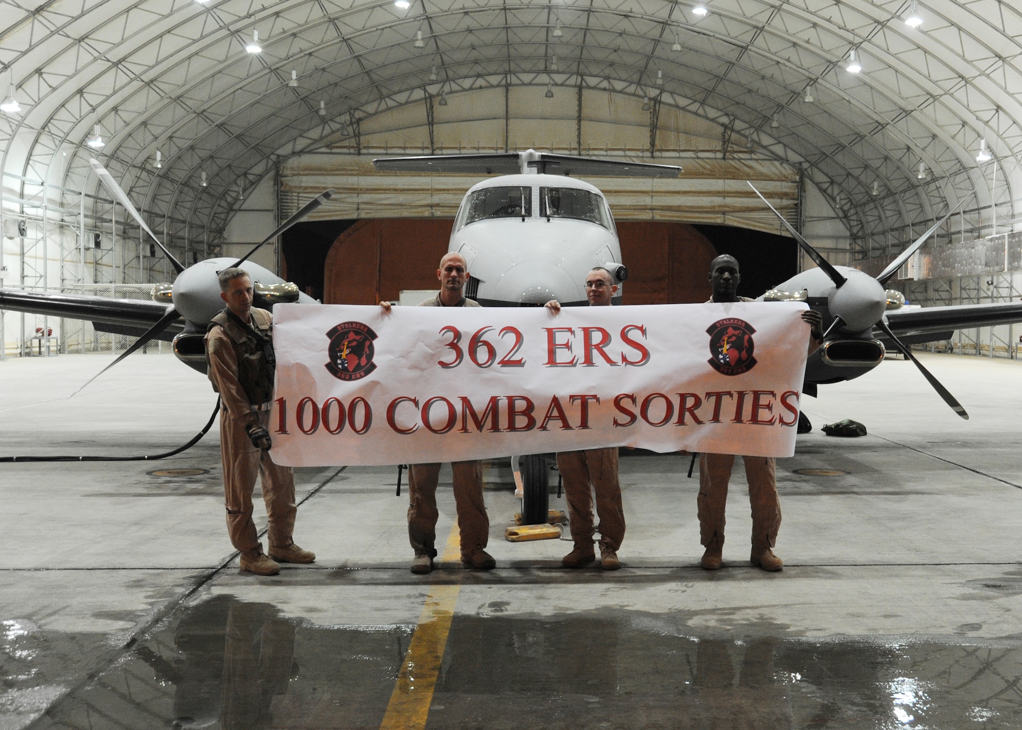 JOINT BASE BALAD, Iraq -- Staff Sgt. Bradley Gray, Tech Sgt. Jason Comer, Maj. Jason Goodale and Capt. Tolan Hicks, 362nd Expeditionary Reconnaissance Squadron MC-12 flight crew members, hold a banner prior to the 1000th MC-12 combat sortie Nov. 16, 2009. Activated in June 2009, the 362nd reached 1000 missions a few days past their five-month mark. (U.S. Air Force photo/Senior Airman Christopher Hubenthal)