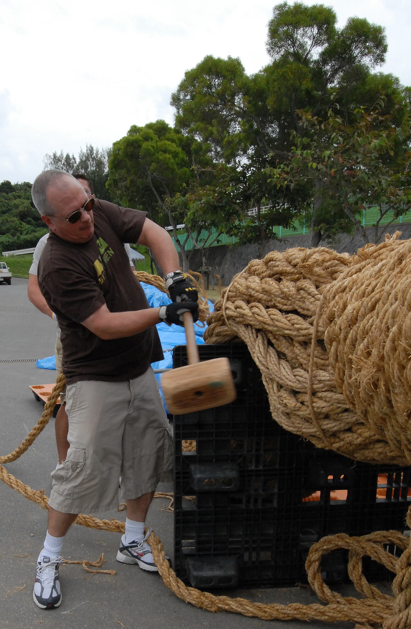 Master Sgt. Michael Waterman, Det. 1, 554th Red Horse Squadron, tightens ropes with a sledgehammer as volunteers build part of a 3-ton tug-of-war rope Nov. 15. The road outside Kadena's Gate 2 will be closed to vehicle traffic from 11 a.m. to 9 p.m. Nov. 21-22 as Okinawa City holds its annual International Carnival and Gate 2 Street Fest. (Air Force/Staff Sgt. Jason Lake)