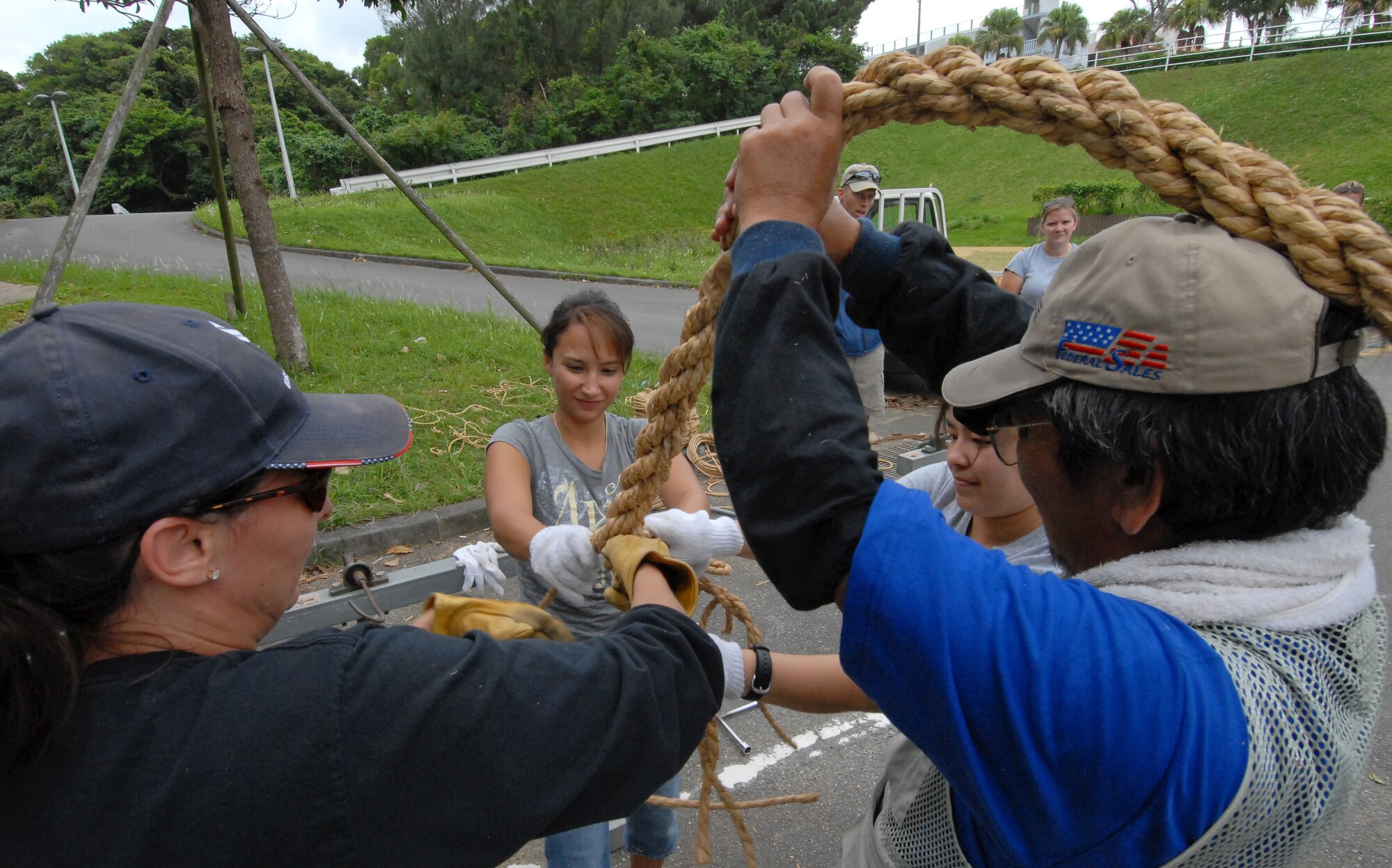 Kris Waterman, wife of Master Sgt. Michael Waterman from Det. 1, 554th Red Horse Squadron, Staff Sgt. Maria Whitworth and Staff Sgt. Linda Castro from the 909th Air Refueling Squadron, and Seiei Gakiya, Koza Gate 2 Street president, twist three separate strands of rope together to add to Okinawa City's tug-of-war rope. Volunteers from Kadena and neighboring communities came together Nov. 15 to help put together pieces of a 3-ton, 300-yard long tug-of-war rope that will be used in the Okinawa City International Carnival and Gate 2 Fest Nov. 21. The tug-of-war, which is one of the highlights of the two-day festivities, begins at 6 p.m. on Gate 2 Street off base. (Air Force/Staff Sgt. Jason Lake)