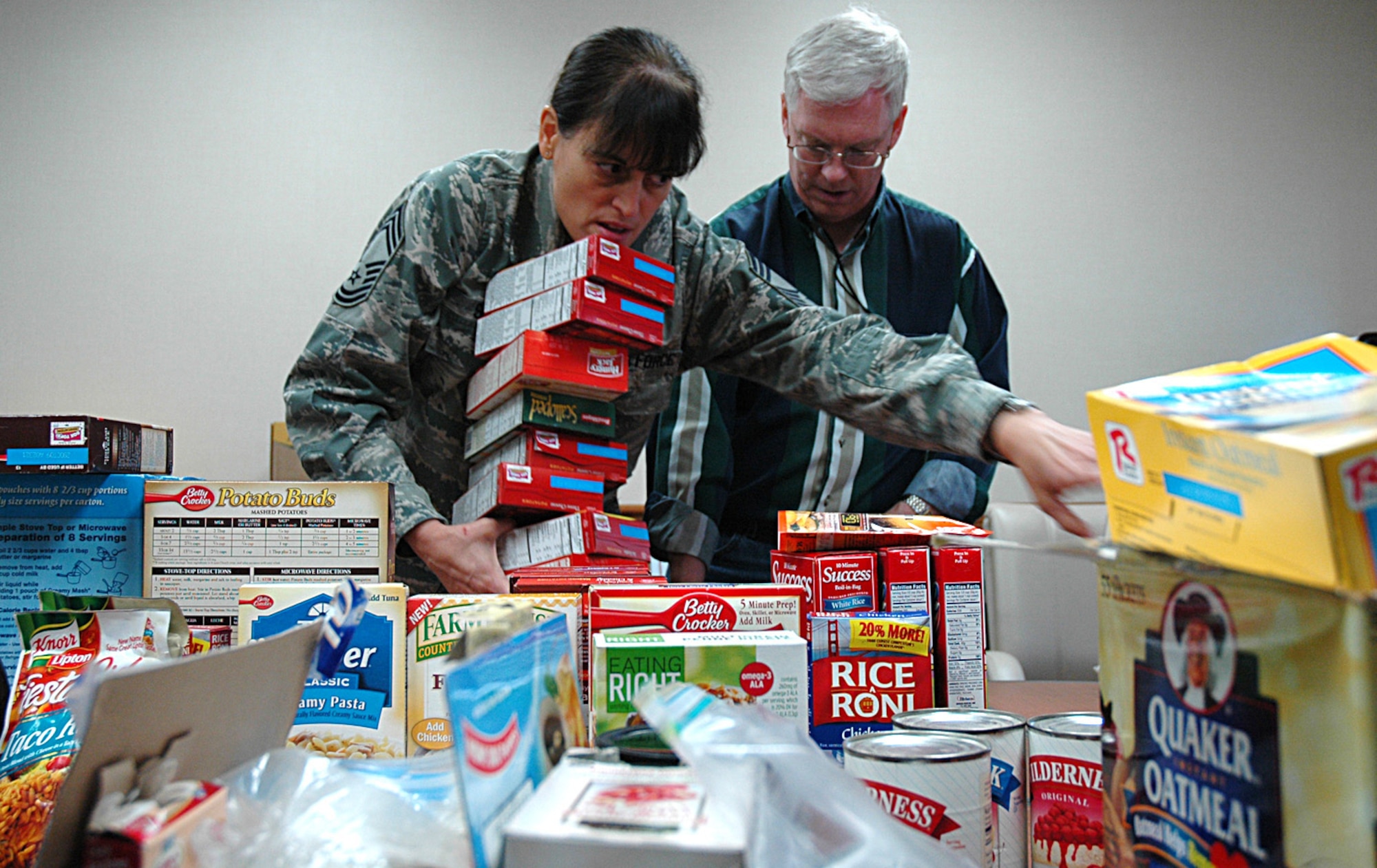 MCCHORD AIR FORCE BASE, Wash., - Chief Master Sgt. Mary Smith, 97th Airlift Squadron (left), and Carl Supplee, director of the 446th Mission Support Squadron's Airmen & Family Readiness Center here, sort through food donations as they and nine volunteers put together Thanksgiving Day food baskets for Reserve families in need. (U.S. Air Force photo/Sandra Pishner)