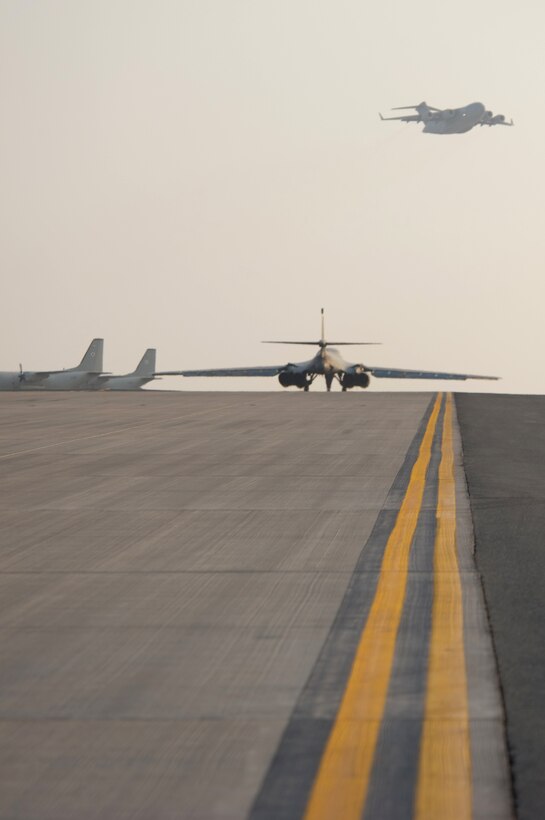 While a C-17 Globemaster III flies overhead, a B1-B Lancer taxis on a runway ready to take-off on a combat mission Nov. 11, 2009, at an air base in Southwest Asia. Carrying the largest payload of guided and unguided weapons in the Air Force inventory, the multi-mission B-1 is the backbone of America's long-range bomber force. (U.S. Air Force photo/Staff Sgt. Robert Barney)
