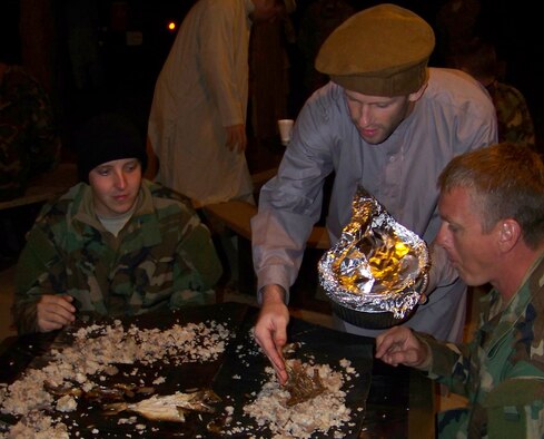 Senior Airman Joshua Lucas (left), and Tech. Sgt. Mark Schroeder (right), both combat aviation advisors with the 19th Special Operations Squadron, go in for another round of rice and water beetles at the request of their guests during the Raven Claw field exercise at the Eglin range Nov. 4. The Airmen were trained in regional skills in preparation for the exercise during the Combat Aviation Advisor Mission Qualification Course. (Air Force photo by Airman 1st Class Joe McFadden.)