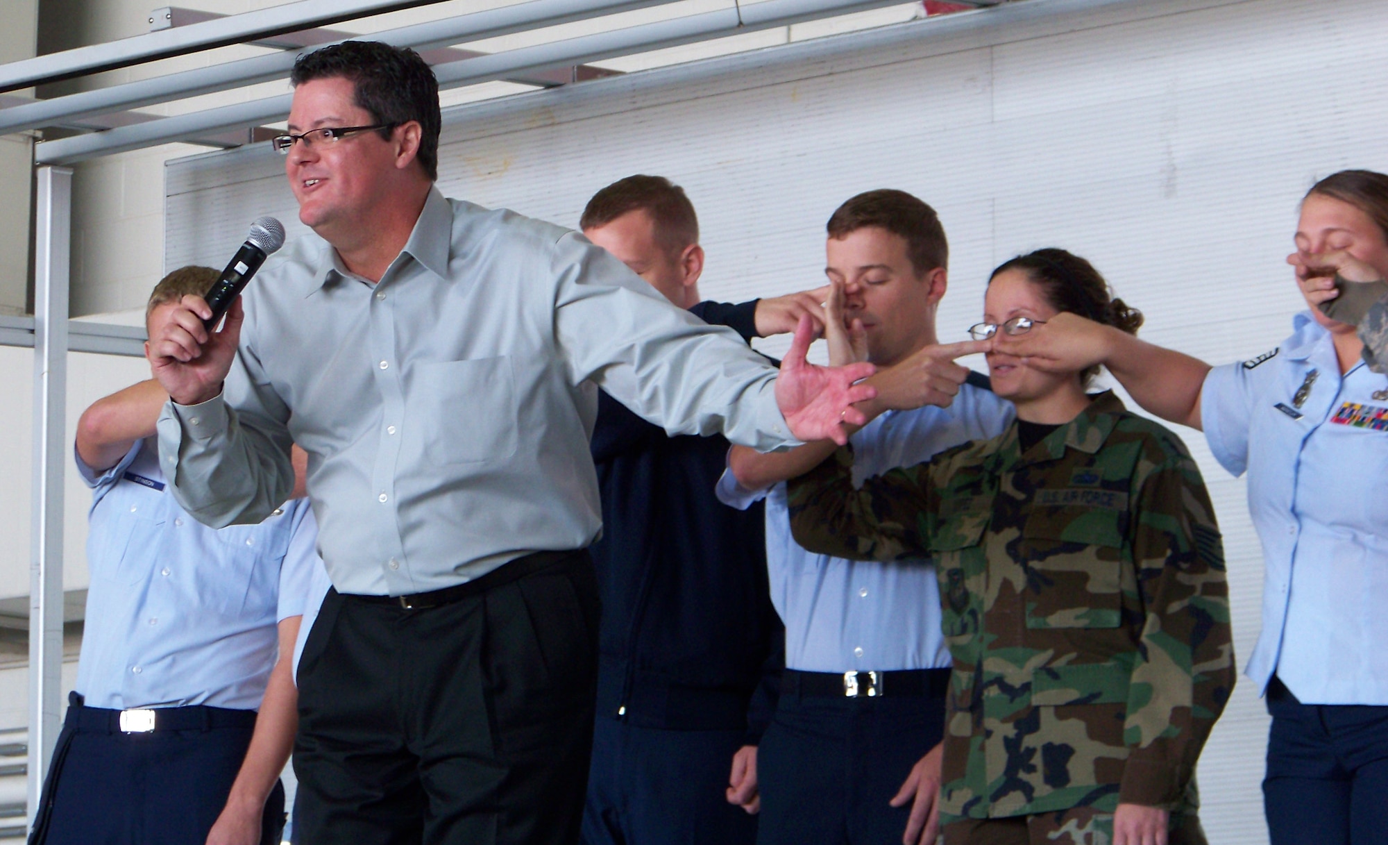 Curtis Zimmerman speaks to the audience while the Airmen onstage touch their neighbor’s nose in the Simon says challenge during a Wingman Day briefing at Freedom Hangar Nov. 16. Mr. Zimmerman also led coordination exercises and juggling demonstrations as part of his presentation. (Air Force photo by Airman 1st Class Joe McFadden.)