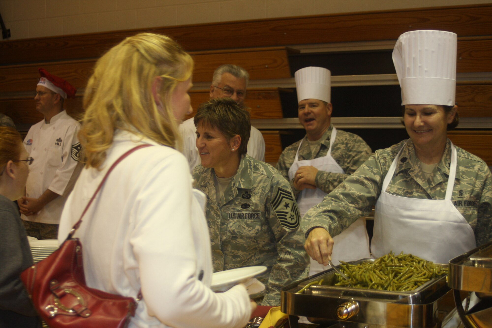 WRIGHT-PATTERSON AIR FORCE BASE, Ohio - Two reservists from the 445th Airlift Wing volunteered at the base’s annual Airman’s Homestyle Thanksgiving dinner Nov. 17 at the Jarvis Gym.  Lt. Col. Linda Stokes-Crowe, 445th Aeromedical Evacuation Squadron commander, and Chief Master Sgt. Peri Rogowski, 445th Airlift Wing command chief, sported chefs hats and aprons to serve Thanksgiving meals alongside commanders, first sergeants, and other volunteers from across the base to single/unaccompanied Airmen and family members of deployed personnel.  Sponsored by the 88th Air Base Wing Chaplain’s office, and coordinated by Chaplain (Capt.) William Spencer, 88th ABW chaplain’s office, Airmen enjoyed a night of music from the U.S. Air Force Band of Flight, and a home-style cooked Thanksgiving dinner prepared by the Wright-Patterson Club. (U.S. Air Force photo/Stacy Vaughn)