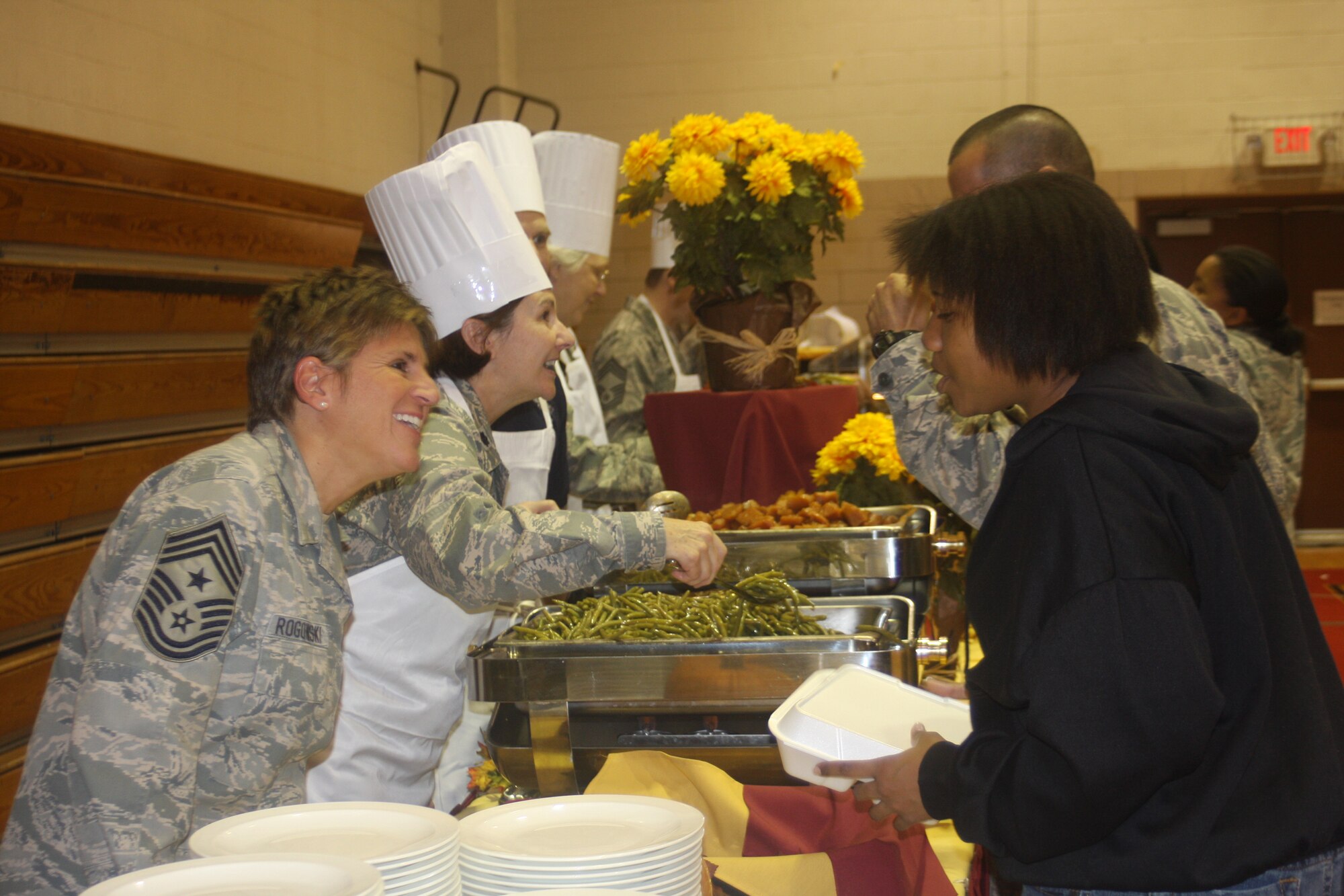 WRIGHT-PATTERSON AIR FORCE BASE, Ohio - Two reservists from the 445th Airlift Wing volunteered at the base’s annual Airman’s Homestyle Thanksgiving dinner Nov. 17 at the Jarvis Gym.  Lt. Col. Linda Stokes-Crowe, 445th Aeromedical Evacuation Squadron commander, and Chief Master Sgt. Peri Rogowski, 445th Airlift Wing command chief, sported chefs hats and aprons to serve Thanksgiving meals alongside commanders, first sergeants, and other volunteers from across the base to single/unaccompanied Airmen and family members of deployed personnel.  Sponsored by the 88th Air Base Wing Chaplain’s office, and coordinated by Chaplain (Capt.) William Spencer, 88th ABW chaplain’s office, Airmen enjoyed a night of music from the U.S. Air Force Band of Flight, and a home-style cooked Thanksgiving dinner prepared by the Wright-Patterson Club. (U.S. Air Force photo/Stacy Vaughn)