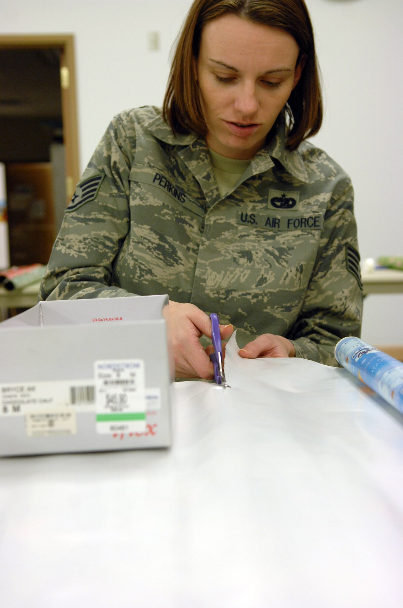 Staff Sgt. Jeanne Perkins cuts wrapping paper Nov. 11, 2009, Eielson Air Force Base, Alaska. Volunteers gathered at the base chapel to wrap shoeboxs filled with candy, toys and toiletries for children around the world as a part of Operation Christmas Child. Sergeant Perkins is an Airman Leadership School instructor. (U.S. Air Force photo/ Airman 1st Class Rachelle Coleman)