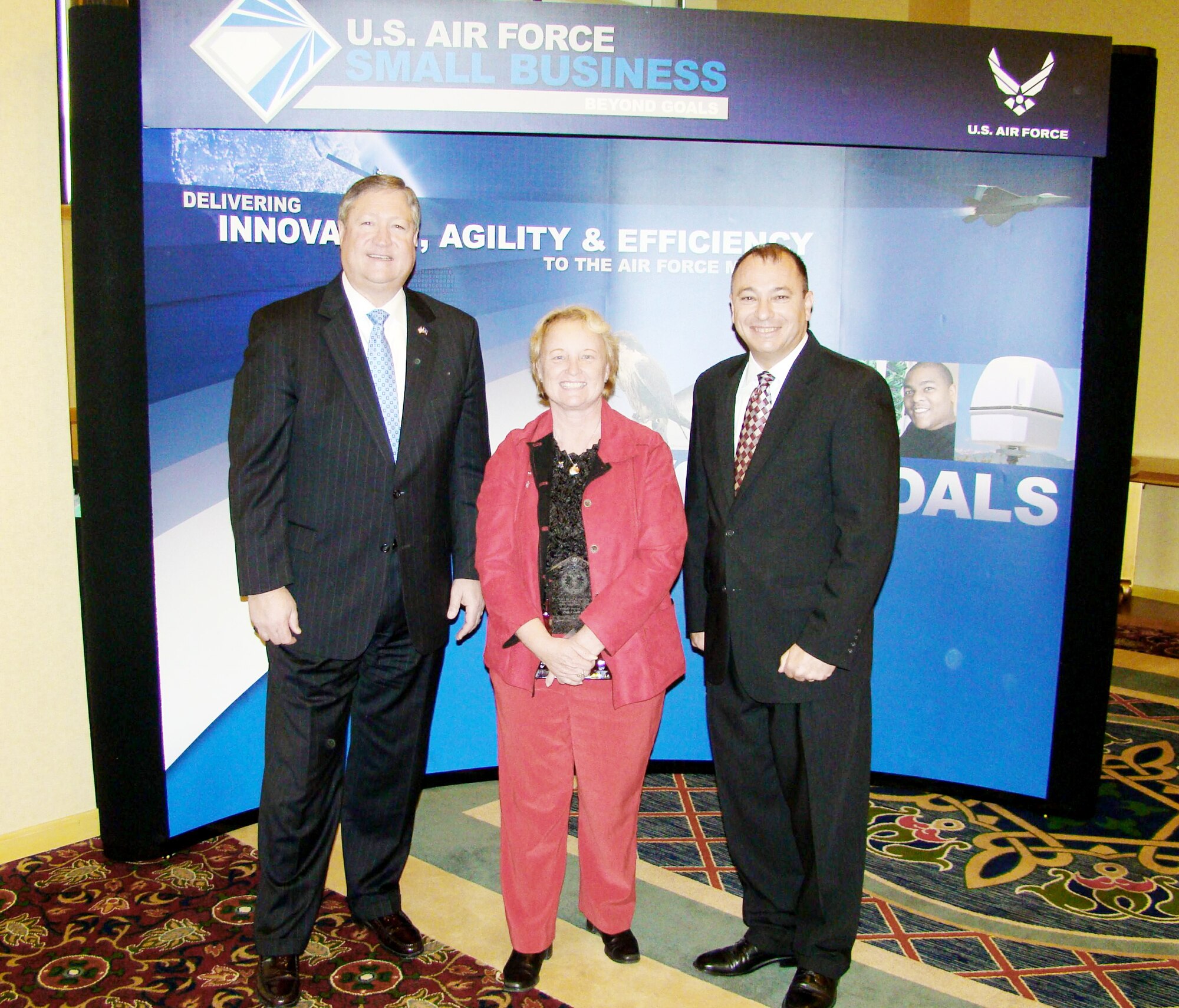 Secretary of the Air Force Michael B. Donley (left) and Ronald A. Poussard stand with Diane Perry, recipient of the 2008 Air Force Small Business Champion Award, after the awards ceremony Nov. 17, 2009, in Arlington, Va. Ms. Perry received the award for her accomplishments as the small business specialist for Vandenberg Air Force Base, Calif. Mr. Poussard is the Air Force Office of Small Business Programs director. (Courtesy photo)