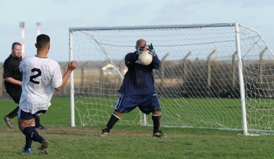 RAF MILDENHALL, England -- Eduard Dedousis, 100th Logistics Readiness Squadron player, attempts to score on  Dana Gold, 100th Communications Squadron goalie, in an intramural soccer playoff game at the Hardstand Fitness Center Nov. 17. The 100th LRS progressed to the championship game with the 4-1 win. (U.S. Air Force photo/Senior Airman Thomas Trower)