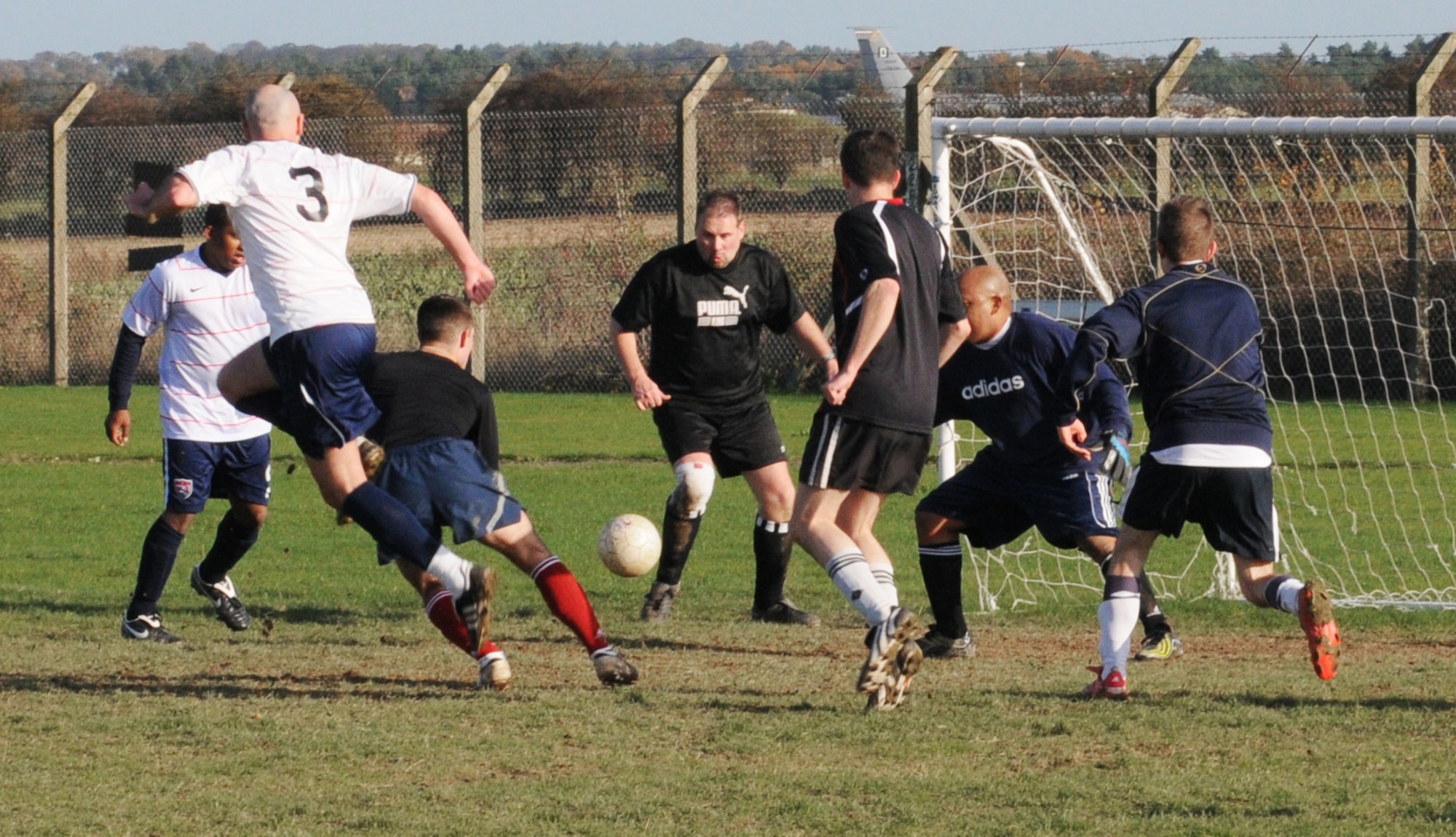 RAF MILDENHALL, England -- Players for the 100th Logistics Readiness Squadron (white) and 100th Communications Squadron scramble for possession of the ball in an intramural soccer playoff game at the Hardstand Fitness Center Nov. 17. The 100th LRS progressed on to the championship match with the 4-1 win thanks to a hat trick by Ray Wisdom. (U.S. Air Force photo/Gary Rogers)