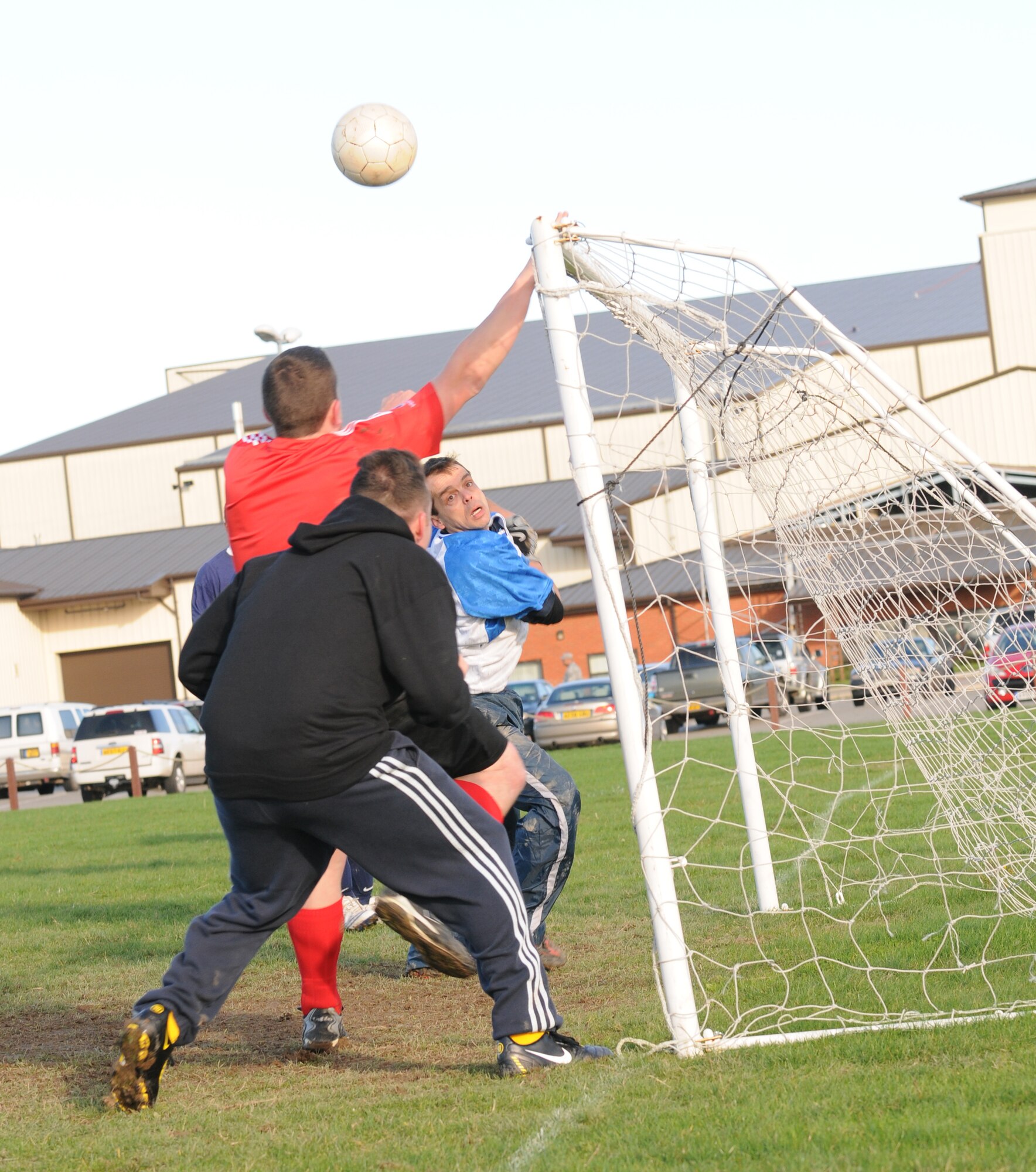 RAF MILDENHALL, England – James Cotton (red ), 727th Air Mobility Squadron player, tries to get on the end of a cross in the intramural soccer play-off game at the Hardstand Fitness Center  Nov. 17. After extra-time, the 488th Intelligence and 95th Reconnaissance Squadrons defeated the 727th AMS 4-3 to advance to the semi-finals.(U.S. Air Force photo/Senior Airman Tomas Trower)