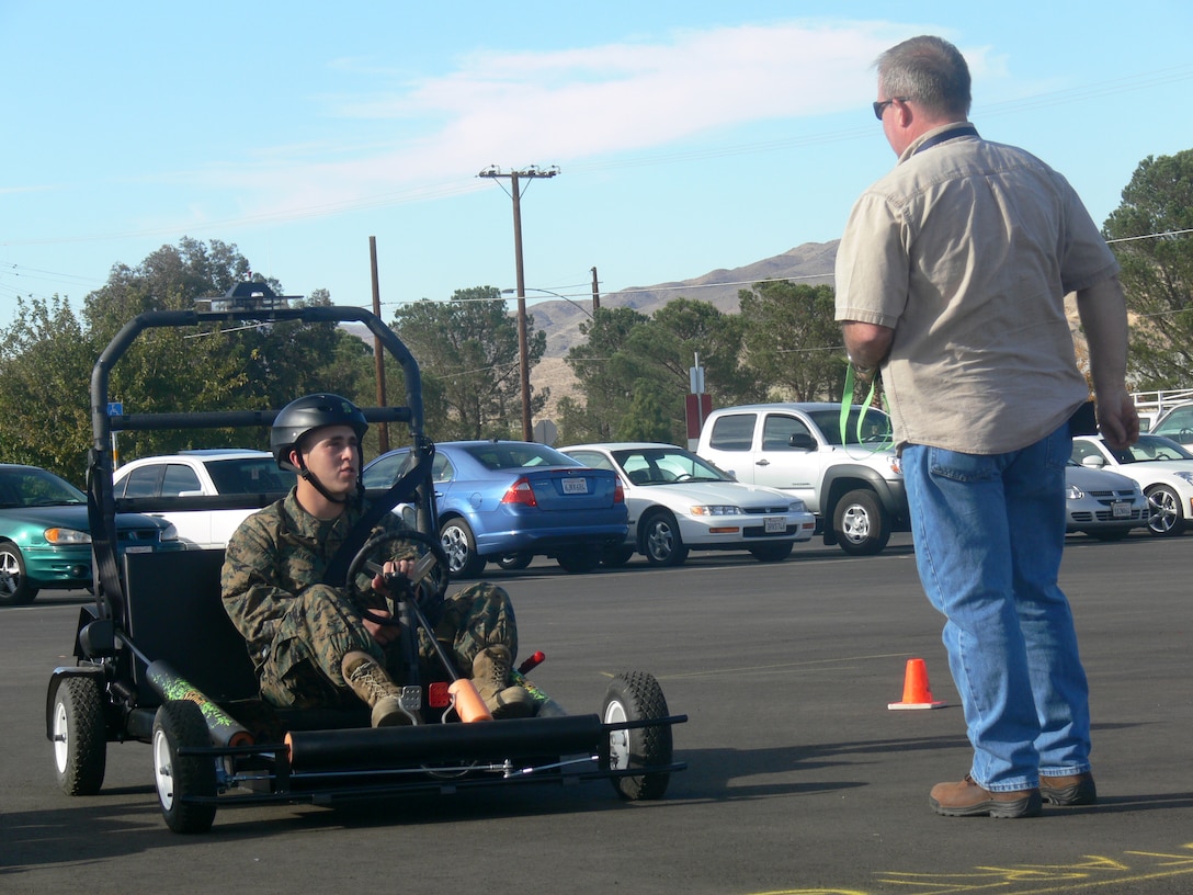 Toledo, Ohio, native Pfc. Jimmy Cryan (left), a separations clerk with Headquarters Battalion, Marine Corps Logistics Base, Barstow, Calif., receives safety instructions from Charlie Keegan, a base safety specialist, before maneuvering through the Simulated Impaired Driving Experience at the MCLBB Parade Deck, Nov. 12. The "SIDNE" driving simulator is designed to teach Marines about the dangers of drinking and driving and how alcohol consumption can impair both judgment and a driver's ability to react to dangerous traffic and road conditions.