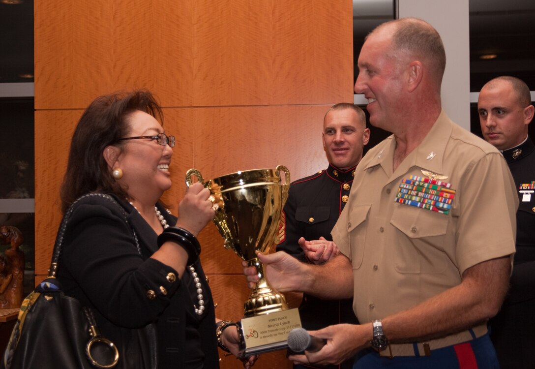 Colonel Robert Rice, Commander, Marine Corps Base Hawaii, presents Merrill Lynch Vice President Diane Kimura with the first place Tricycle Cup Competition trophy during a Toys for Tots corporate sponsors’ reception Nov. 19. Merrill Lynch employees donated the most toys among downtown businesses during the Tricycle Cup toy collection competition which was held Nov. 17.