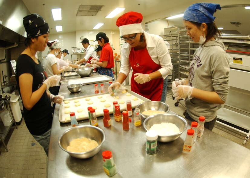 Students from the Kadena Language Institute and Nikkei Business School, along with military dependents, prepare cookies for servicemembers living in the dorms at Kadena Air Base Nov. 18. The Hometown Kadena Cookie Drive volunteers prepared more than 24,000 cookies that will be delivered to dorm residents by first sergeants and other representatives Dec. 14. "It's our way of giving them a little taste of home," said Mrs. Sheri Fletcher, one of the event coordinators. 
(U.S. Air Force photo/Tech. Sgt. Rey Ramon) 

