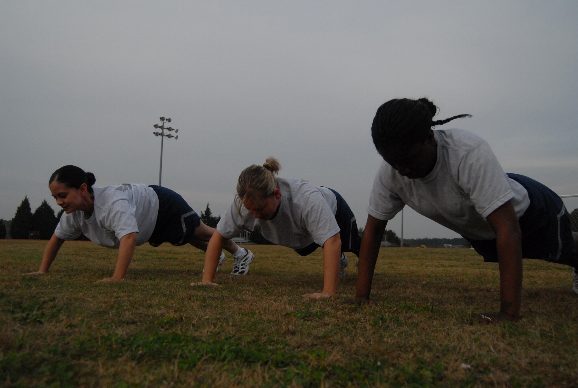 Tech Sgt. Lorraine Bussart, Staff Sgt. Crystal Parcell and Staff Sgt. Nadia Rowell, 43rd Medical Operations Squadron, do push-ups at the Pope track Nov. 17. (U.S. Air Force Photo by 2nd Lt. Cammie Quinn)

