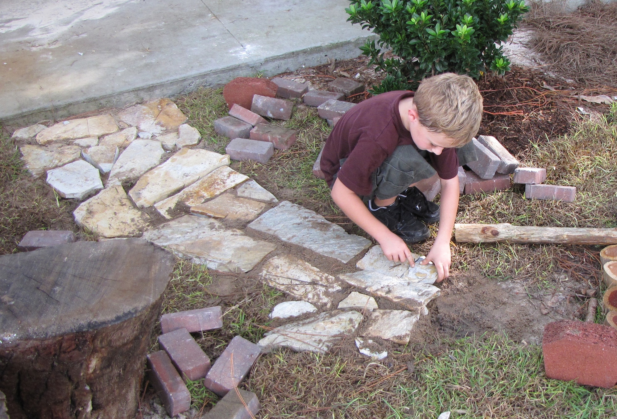 Six-year-old Jared Comeau sets a brick along a pathway at the Hurlburt Field Youth Center’s outdoor classroom Sept. 22. The classroom was the first in the Air Force and state of Florida to earn the national designation of a certified Nature Explore classroom. (Air Force photo courtesy of the Hurlburt Field Youth Center)