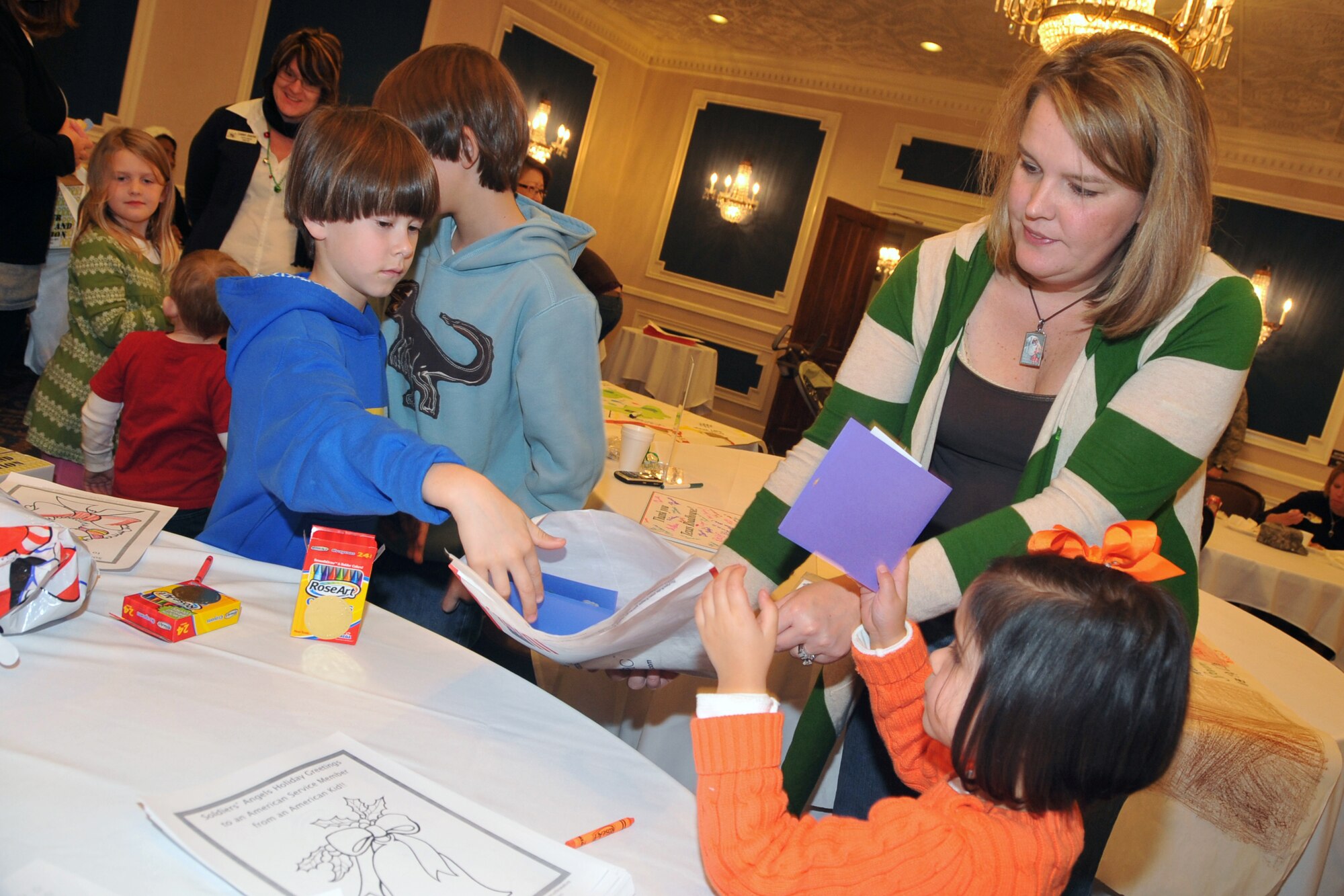 OFFUTT AIR FORCE BASE, Neb. - Alice Rehome, wife of Maj. Paul Rehome, helps her children Brycen, Briggs, Lei La-Anne and Taggert put all of their cards into the package for their father during Holiday Connections Nov. 17 at the Patriot Club. The event, established in 2000, provides support for the loved ones of military members who are deployed during the holiday season. U.S. Air Force photo by Jeff W. Gates 