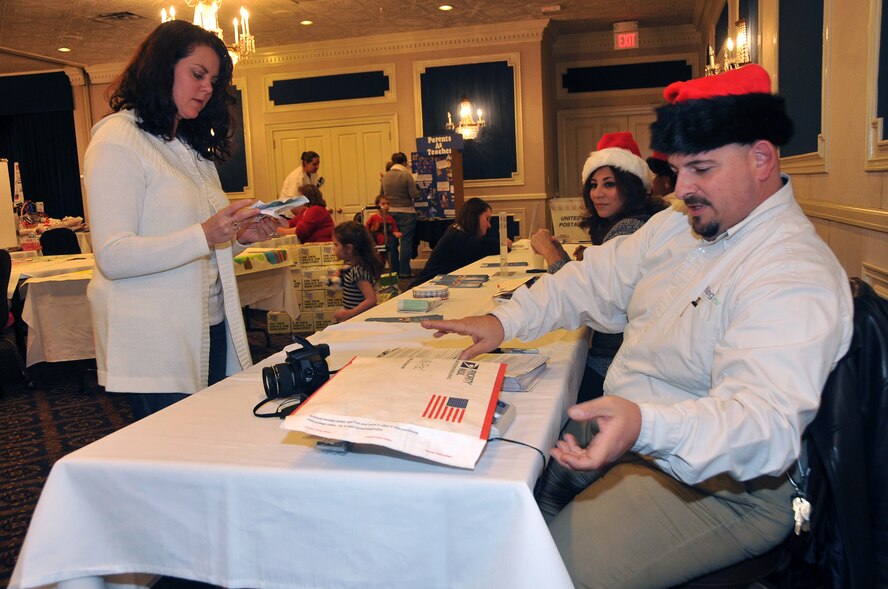 OFFUTT AIR FORCE BASE, Neb. - Devon Cutinella waits as volunteer Chuck Ketchum weighs a care package destined for her husband Maj. Andrew Cutinella, a member of the 38th Reconnaissance Squadron, during Holiday Connections 09 Nov. 17 at the Patriot Club. The event, established in 2000, provides support for loved ones of military members deployed during the holiday season. U.S. Air Force photo by Jeff W. Gates