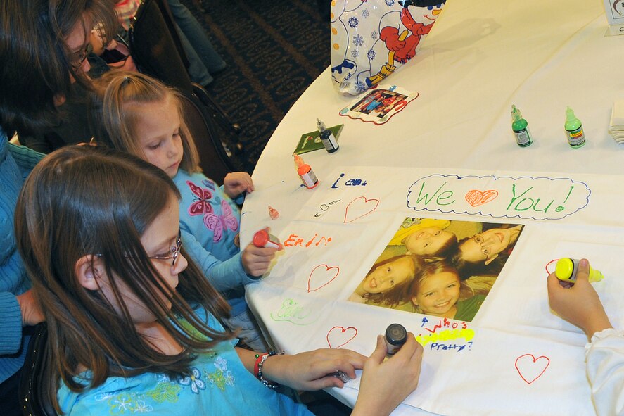 OFFUTT AIR FORCE BASE, Neb. - (From left) Five-year-old Leah Harroun, and her sister 11-year-old Erin design a special pillow case for their father, Master Sgt. Terry Harroun with the 97th Intelligence Squadron during Holiday Connections 09.  The event, held Nov. 17 in the Patriot Club, was established in 2000 to provide support for loved ones of military members  deployed during the holiday season. U.S. Air Force photo by Jeff W. Gates