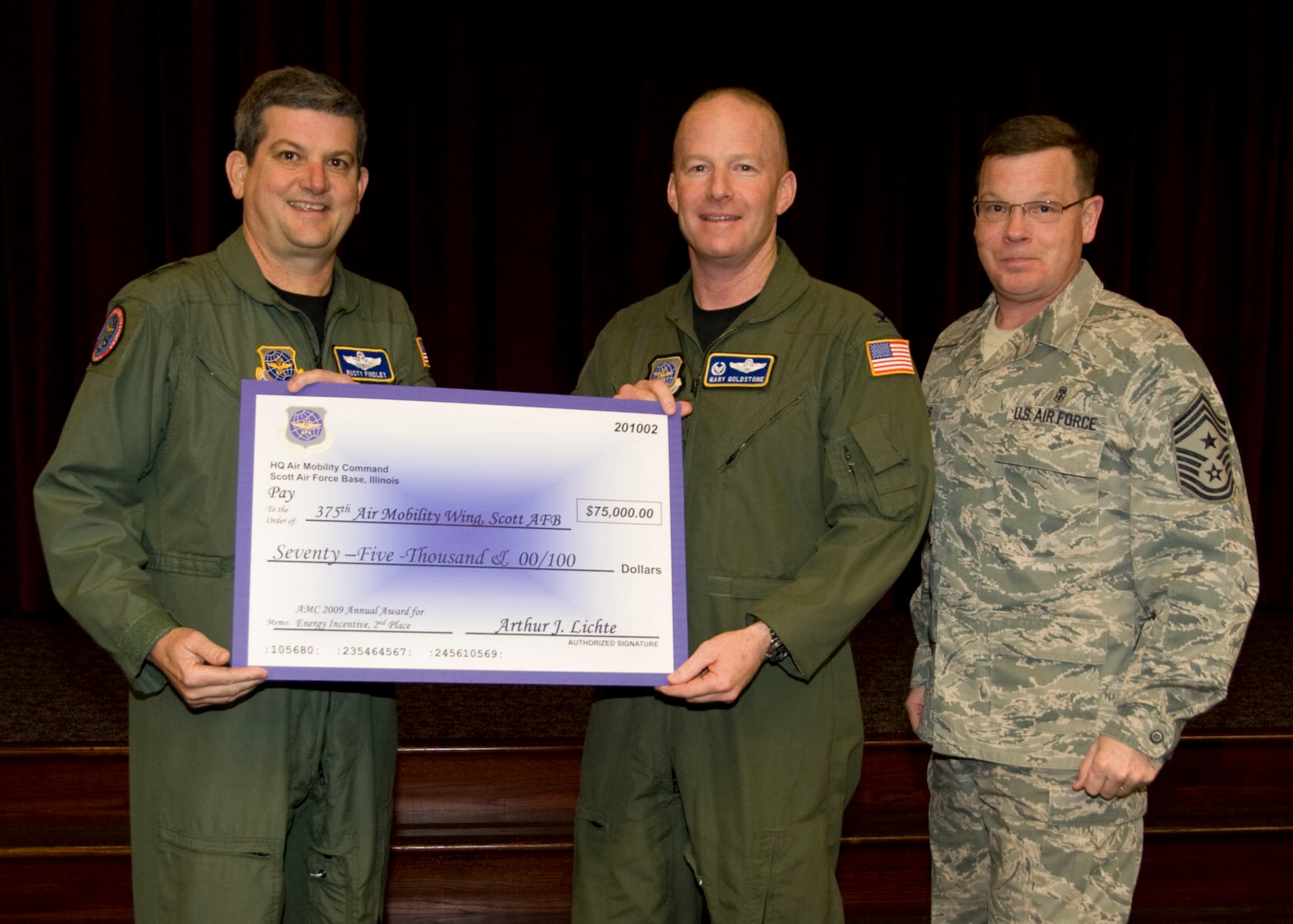 SCOTT AIR FORCE BASE, Ill. -- Lt. Gen. Vern M. Findley II, Air Mobility Command vice commander presents Col. Gary P. Goldstone, 375th Air Mobility Wing commander and Command Chief Master Sgt. James Suttles, 375th AMW command chief with a $75,000 check for 2nd place in AMC's 2009 Annual Award for Energy Incentive. (Courtesy Photo) 