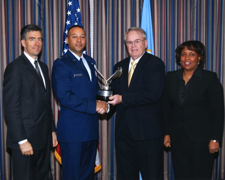 (Left to right) Mr. John Inglis, National Security Agency Deputy Director, presents the NSA’s 19th Annual Frank B. Rowlett Trophy for Individual Achievement to Capt. Jamal P. Quinnert, Air Force Operational Test and Evaluation Center Detachment 3 Information Assurance Branch Chief at Kirtland Air Force Base, N.M., with Mr. Thomas M. Rowlett, son of the late Mr. Frank B. Rowlett, and Mrs. Debora A. Plunkett, NSA Deputy Director of Information Assurance, assisting. The award is named in honor of crypto logic pioneer Frank B. Rowlett to recognize significant contributions to the information assurance discipline.