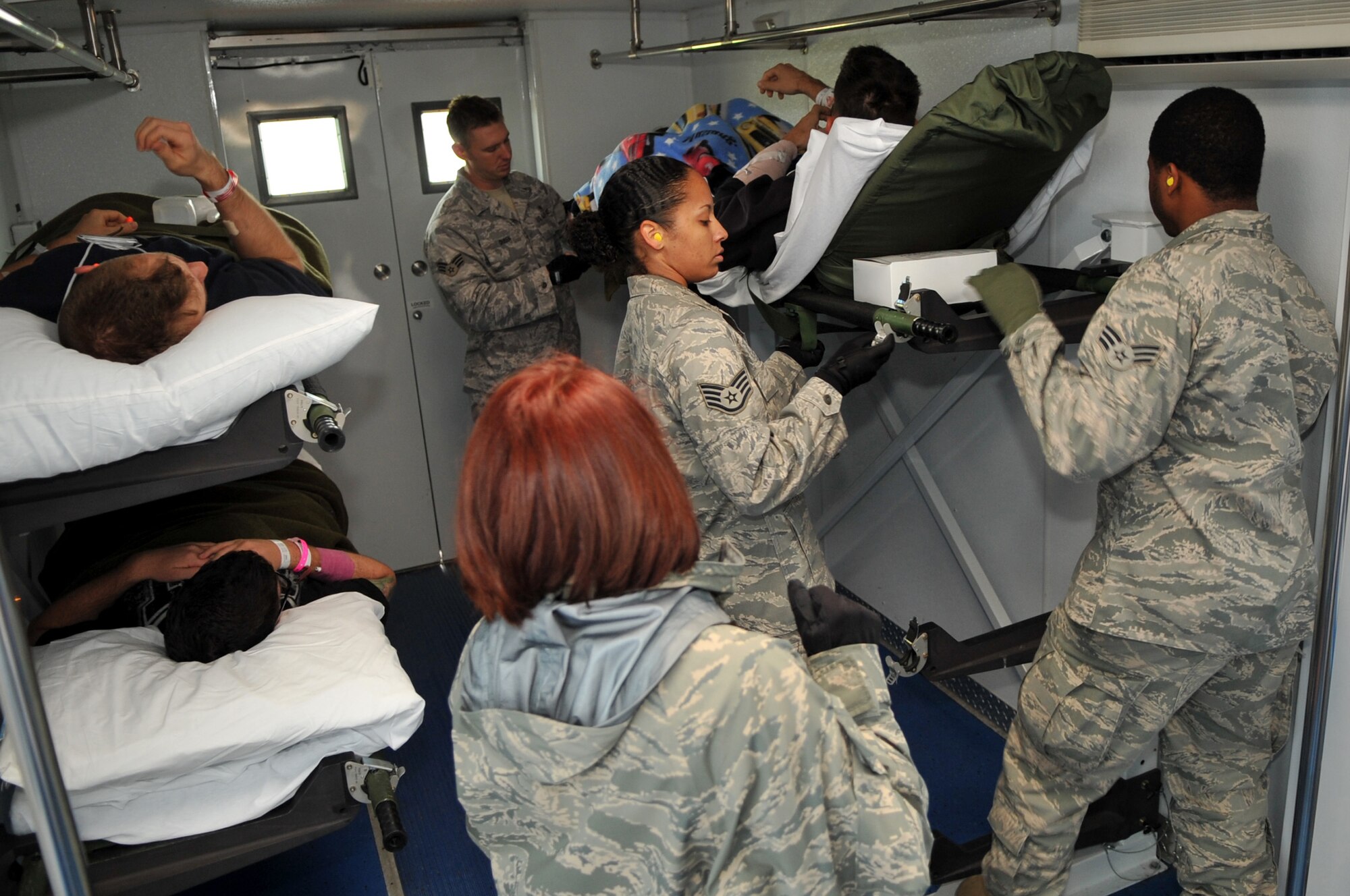 SCOTT AIR FORCE BASE, Ill -- Staff Sgt. Beverly Jones (front left) 375th Aeromedical Staging Flight (ASF), Senior Airmen Alex Altman (front right) 375th Medical Operations Squadron and Senior Airmen Dane Queen (back) 375th Aeromedical Staging Flight Members secure a litter on the ASF's high deck patient loading platform truck Nov. 18. Members of the ASF transferred a total of 11 injured military personnel from a KC-135 to a C-130. Patients were transported from downrange to Landstuhl, Germany to Andrews AFB to Scott AFB and on to their various final destinations across the US.  (U.S. Air Force photo by Senior Airmen Teresa M. Jennings)