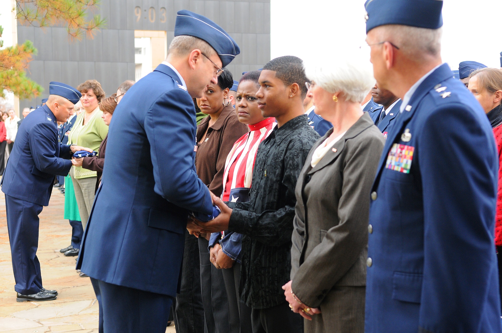 Friends and family of Airman 1st Class LaKesha Richardson Levy, including her son Corey Levy and mother Constance Favorite (red and white stripes), accept a flag from 72nd Medical Group commander, Col. Robert Marks, during a Veterans Day wreath laying ceremony at the Oklahoma City National Memorial as Oklahoma City Air Logistics Center commander, Maj. Gen. David Gillett, and his wife Stacia look on. Far left, Col. Thomas Byrge, 3rd Combat Communications Group commander, presented a flag to the family of Airman 1st Class Cartney Jean McRaven. Both Airmen were killed in the April 19, 1995, bombing of the Alfred P. Murrah Federal Building. Earlier, General and Mrs. Gillett laid wreaths on the Airmen’s memorial chairs. (Air Force photo by Dave Faytinger)