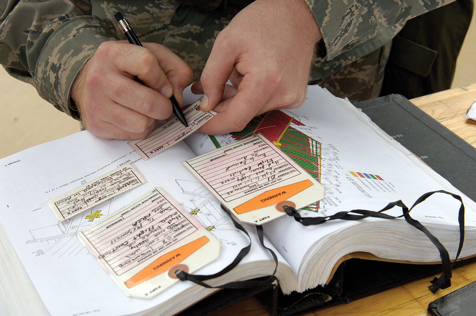 To protect Expeditionary Depot Maintenance technicians, Tech. Sgt. Lonnie Wilson fills out warning tags to place on aircraft systems being repaired to ensure they aren’t used. The technicians were training in making repairs in a deployed location. (Air Force photo by Margo Wright)