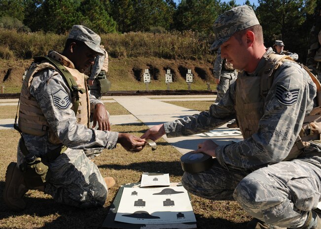 Tech. Sgt. Michael Donaldson hands Master Sgt. Rohan Nugent tape for his target at the Naval Weapons Station Charleston shooting range Nov. 16. The targets were used for weapons qualifications. Sergeant Donaldson is an aircrew flight equipment supervisor for the 437th Operations Support Squadron and Sergeant Nugent is the traffic management office superintendent with the 437th Aerial Port Squadron. (U.S. Air Force photo/Senior Airman Katie Gieratz)(RELEASED)   