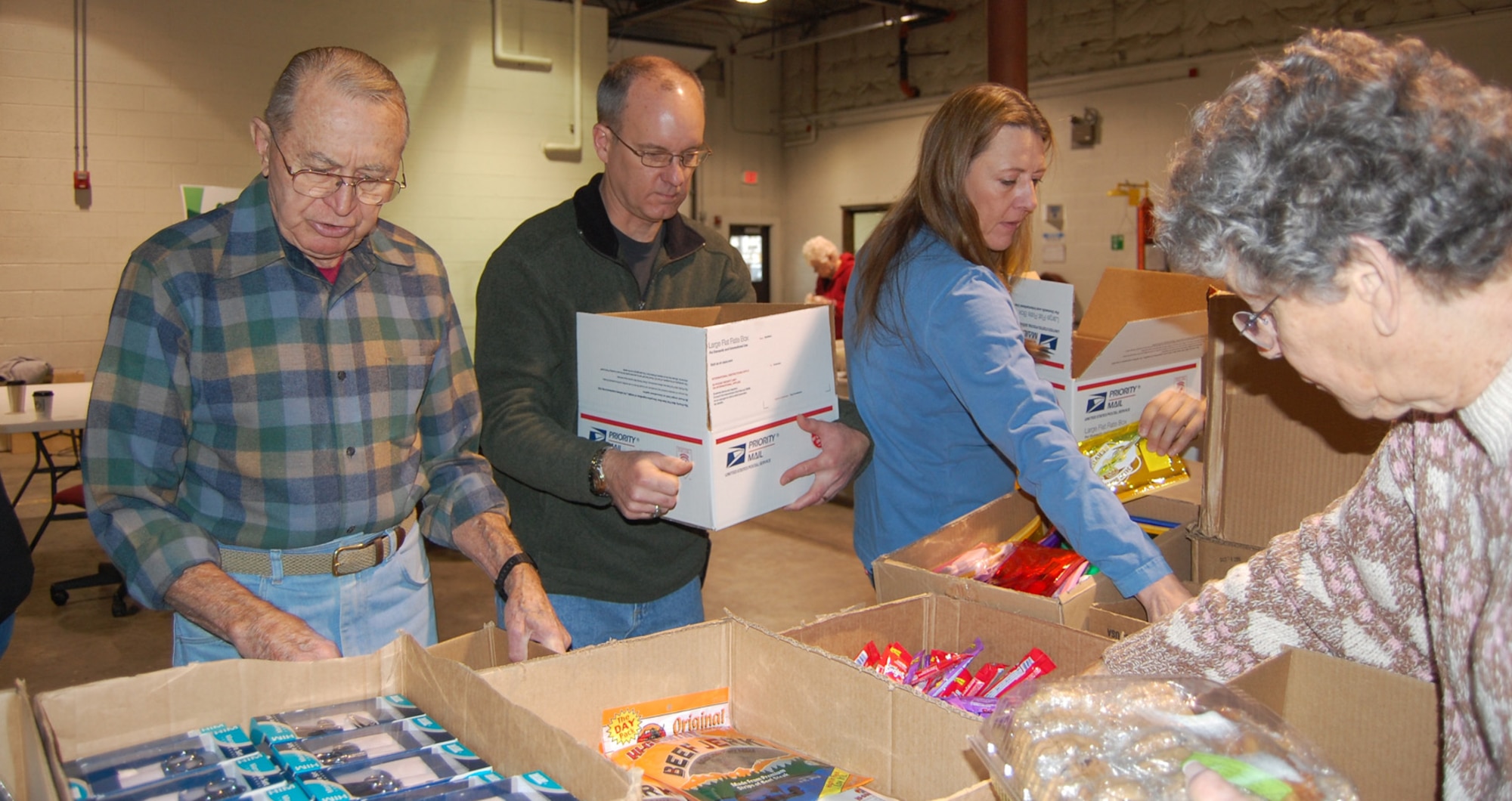 The 341st Missile Wing Commander Col. Michael Fortney and his wife, Karen, help Retiree Council members Scott and Vivian Peterson pack boxes for Operation Happy Holidays 2008. This year's packing event is scheduled Dec. 5 starting at 10 a.m. at bldg. 800. (U.S. Air Force photo/Valerie Mullett)