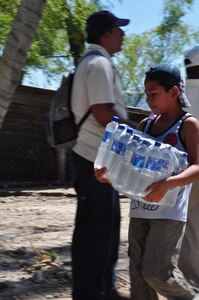 ILOPANGO, El Salvador - A boy carries a case of water that was unloaded off a UH-60 Blackhawk helicopter, assigned to Joint Task Force-Bravo, Nov. 17 near El Sauce, El Salvador. A Civil Affairs team from Special Operations Command South, based out of Homestead, Florida, provided vital aid to the small village of El Sauce by dropping off more than 5,000 total pounds of food and water Nov. 17 and 18. The area was so badly damaged by the floods that villagers had to hand-carry the 5,000 pounds of food almost a quarter of a mile back to the village (U.S. Air Force photo/Staff Sgt. Chad Thompson).