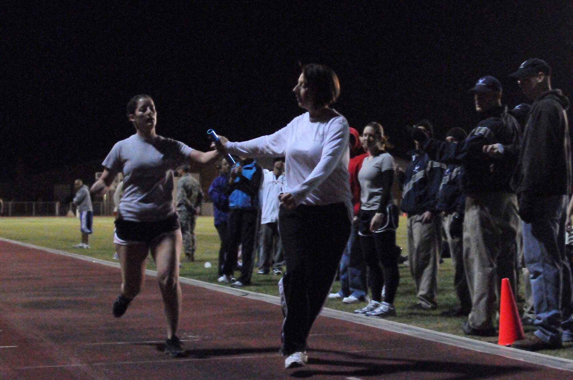 Senior Airman Kelly Figaro, 39th Operations Squadron, hands a baton to Capt. Pamela Defazio, 39th Operations Squadron, during the distance medley race Wednesday, Nov.18, 2009 at the Incirlik track.  The 39th Force Support Squadron and Health and Wellness Center hosted the Under the Lights track meet where squadrons from around the base could compete in various events for points toward a trophy at the end of the event.  (U.S. Air Force photo/Senior Airman Ashley Wood)  