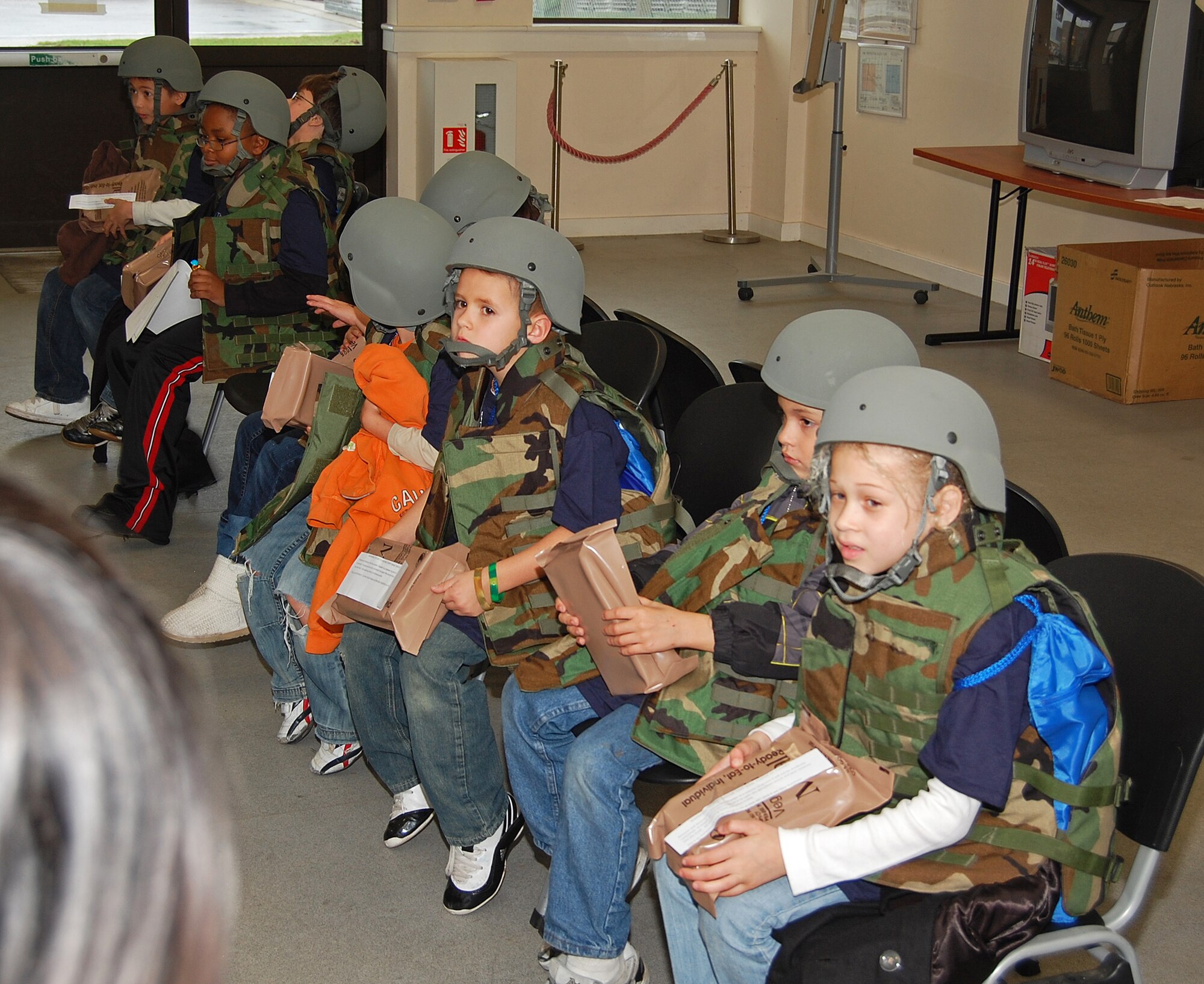 Local children wait for transportation to their deployment location, Camp Cloudy, Iraq, during a mock deployment for children on RAF Lakenheath, England, Nov. 13. The Liberty Wing hosted the event so the children could learn what their parents go through when they deploy. (U.S. Air Force photo by Tim Barlow)