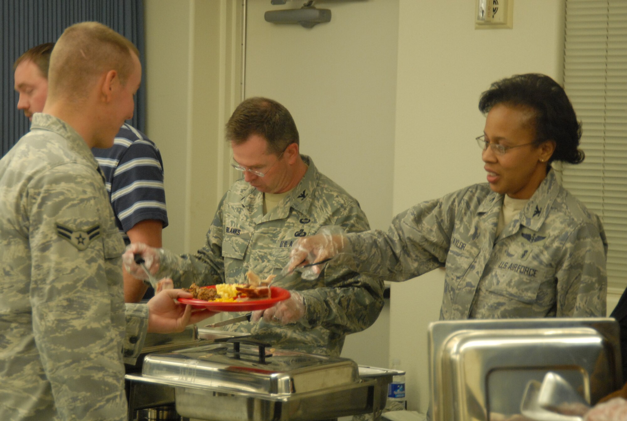 Col. Janet Taylor, 95th Medical Group commander, serves Airman 1st Class Nathan Harris, 95th Security Forces Squadron patrolman, during the Dorm Dwellers Thanksgiving Dinner at the Chapel 1 Annex Nov. 18. The dinner was hosted for all dorm dwellers. (Air force photo/Airman 1st Class William O'Brien)