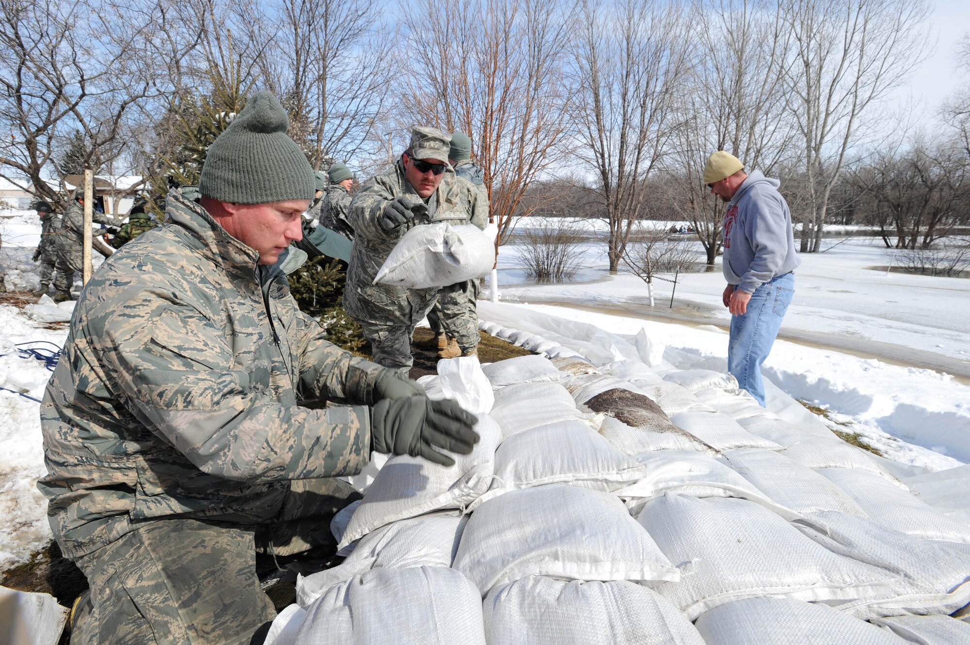 Tech. Sgt. Jon Shumard hands a sandbag to the next position while Tech. Sgt. Kevin Schettler laps the sandbag in place along the Red River March 28, 2009, in south Grand Forks, N.D. He and other Airmen stacked sandbags to increase the dike to a height of 54 feet to mitigate flood damage. (U.S. Air Force photo/Tech. Sgt. Johnny L. Saldivar)