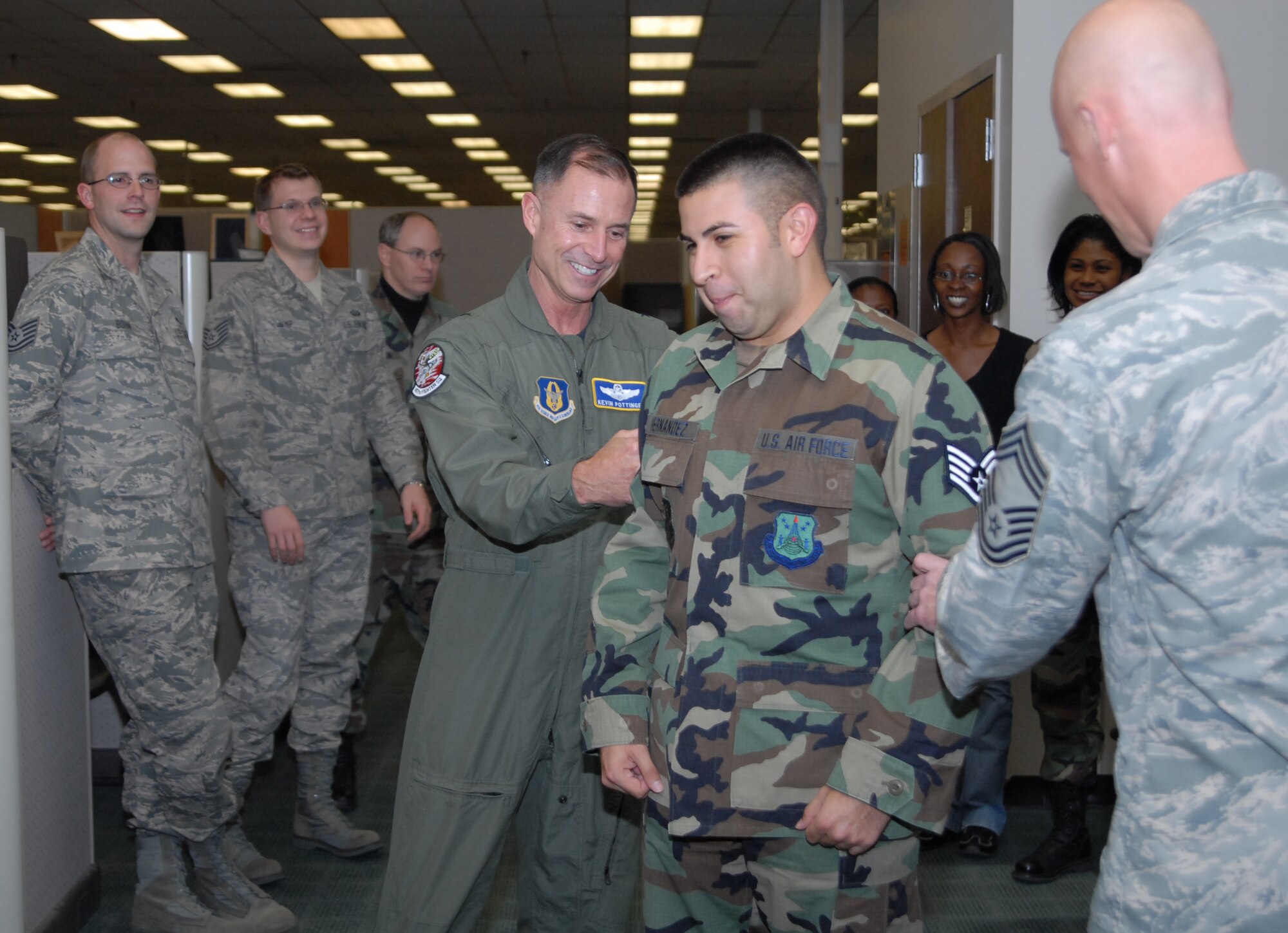 Newly promoted Staff Sgt. Roger Hernandez Jr., a customer service counselor at the Air Reserve Personnel Center, gets his new stripes tacked on by Brig. Gen. Kevin Pottinger, ARPC commander, and Chief Master Sgt. Garrett Vail, Directorate of Personnel Services Superintendent, here Nov. 12. (U.S. Air Force photo by Dwayne Beuthel)